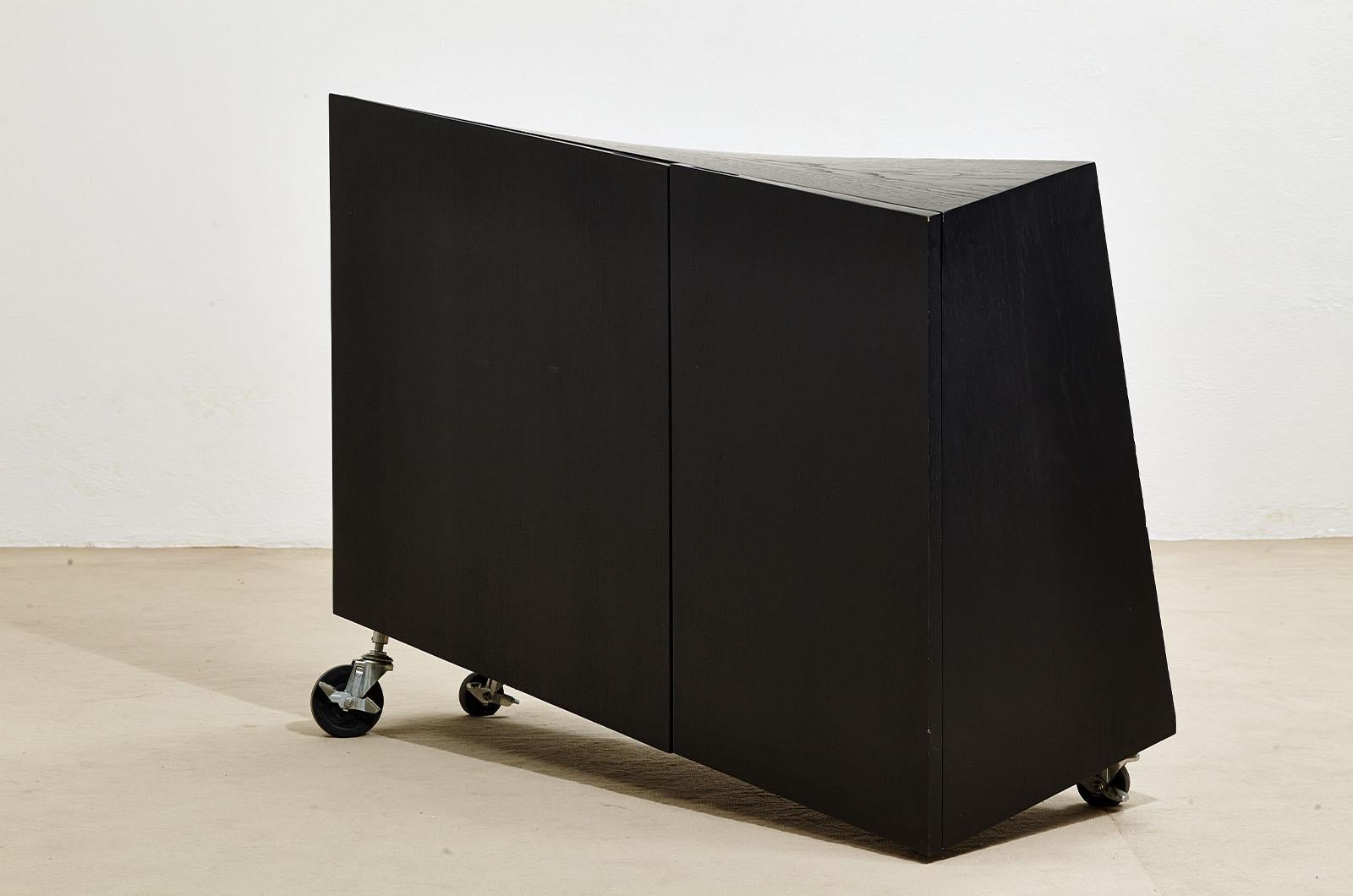 Meubles conçus par Paolo Pallucco et Mireille Rivier en 1988. L'armoire se compose de deux portes à charnières avec un support au sol sur un côté et sur des roulettes de différentes tailles sur les trois autres. Le meuble est fabriqué en frêne