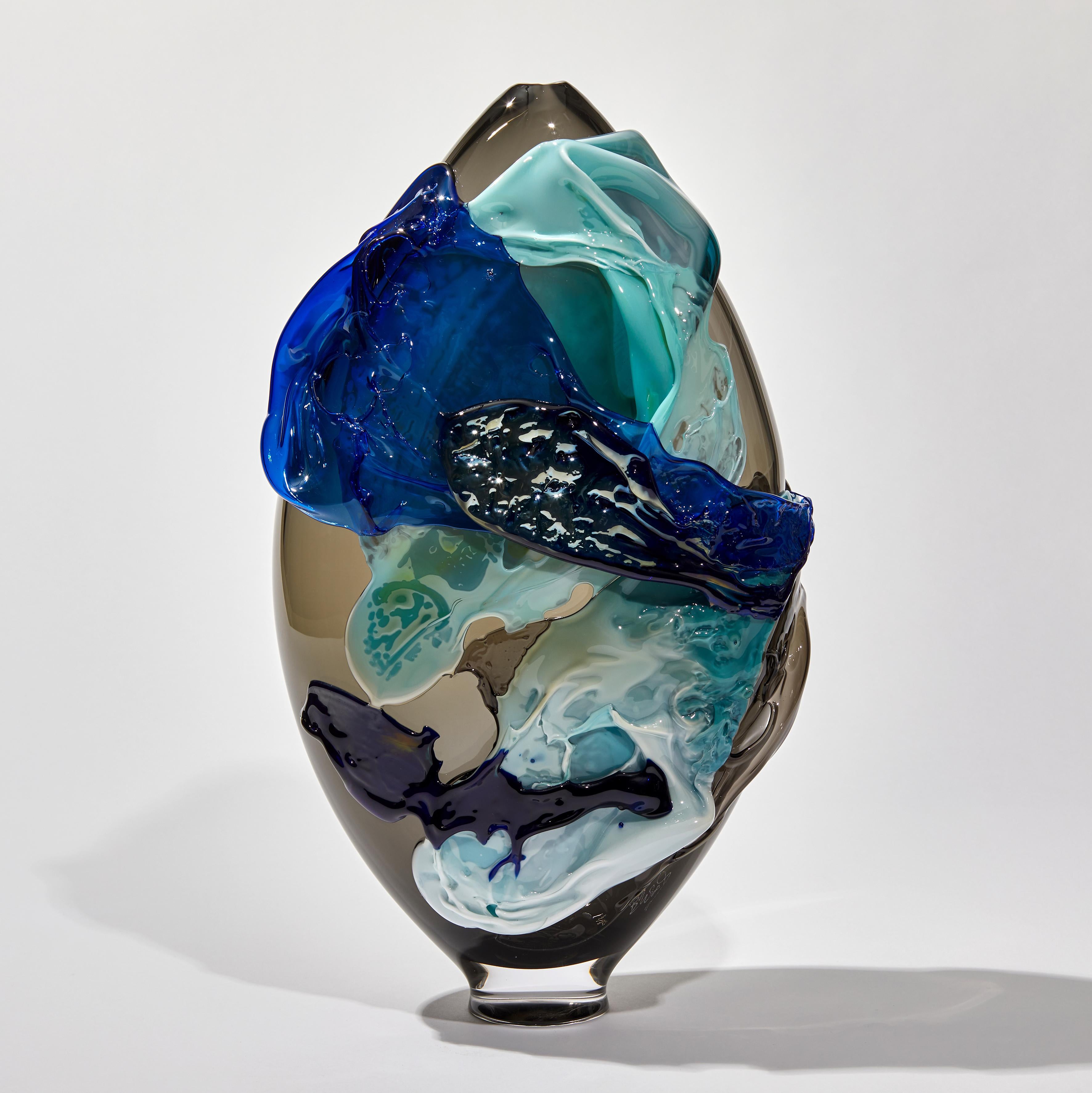 Torrent is a unique blue, aqua, black and smoke glass vase from the Molten Landscapes Collection by the British artist Bethany Wood. An equal passion for painting physically inspires how she controls and manipulates her glass. Recreating the