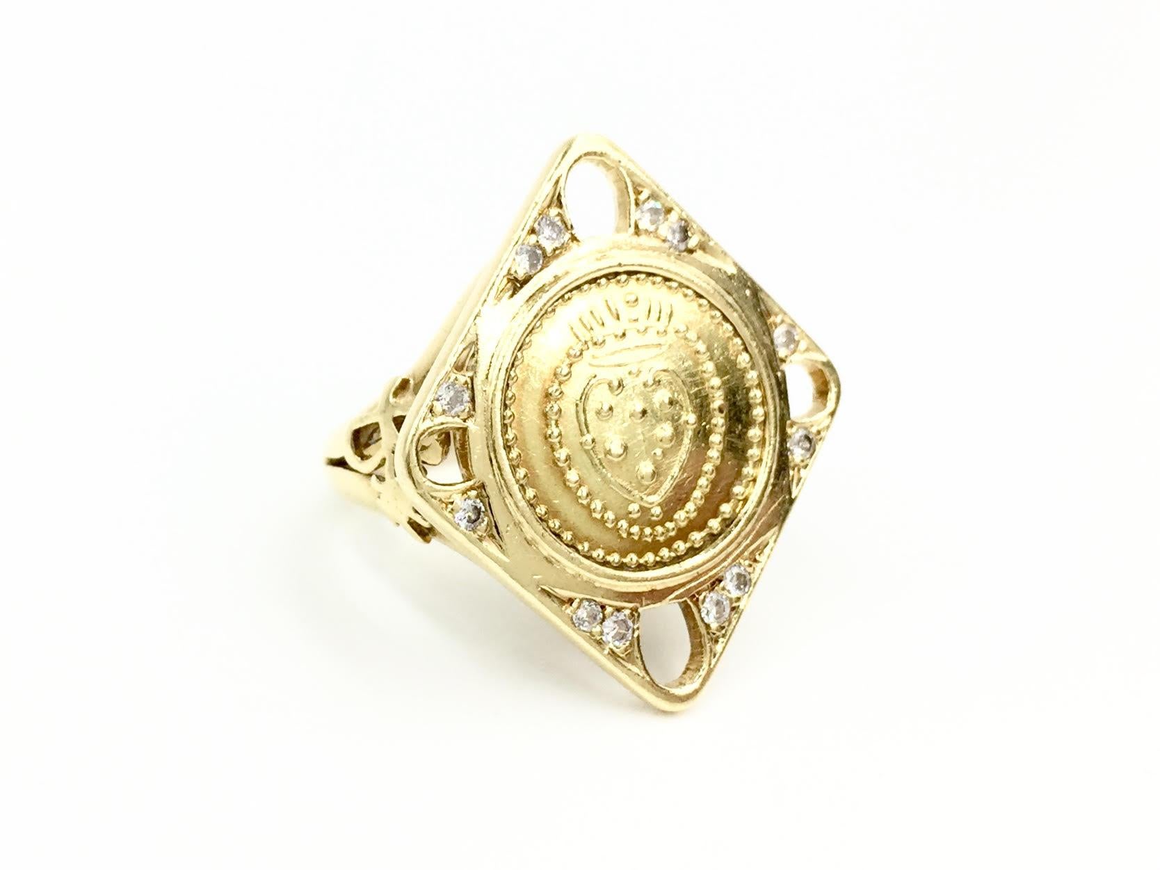 Crafted by expert goldsmith Italian jewelry company, Torrini. This hand made 18 karat yellow gold ring features a beautifully unique square shield design with an engraved round coin in the center. Twelve round diamonds add sparkle to each corner.