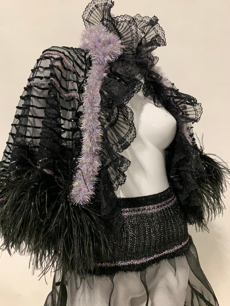Torso Creations 2-piece ensemble: Black tulle net caplet, sequin embellished in a circular motif, ostrich feather hem and iridescent chenille knit trim. High ruffled lace collar. No closure. Skirt is made of knitted lurex yarn waistband and
