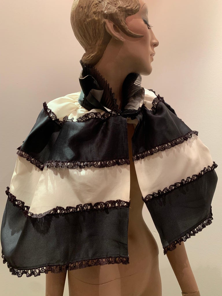 A Torso Creations black and white, silk satin ribbon, organza and lace tiered capelet with ruffled stand-up collar.  Matching gauntlets and large bow headband available--see listings. 