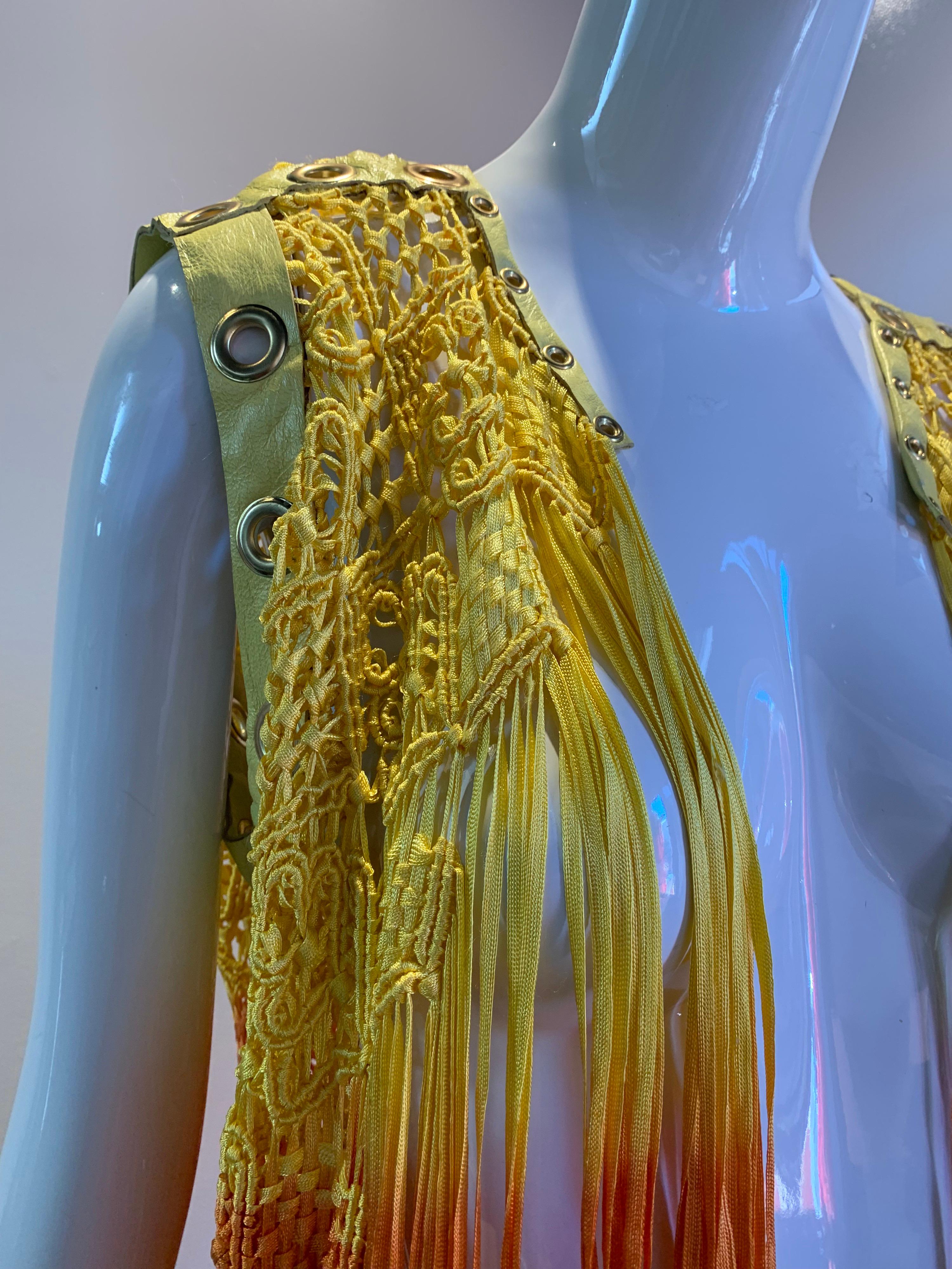 A beautiful, vibrant Torso Creations ombre-dyed rayon ribbon macrame fringe vest with yellow leather trim punctuated with eyelets in colors ranging from canary yellow to a bright reddish-orange.  Can tie at front. 
