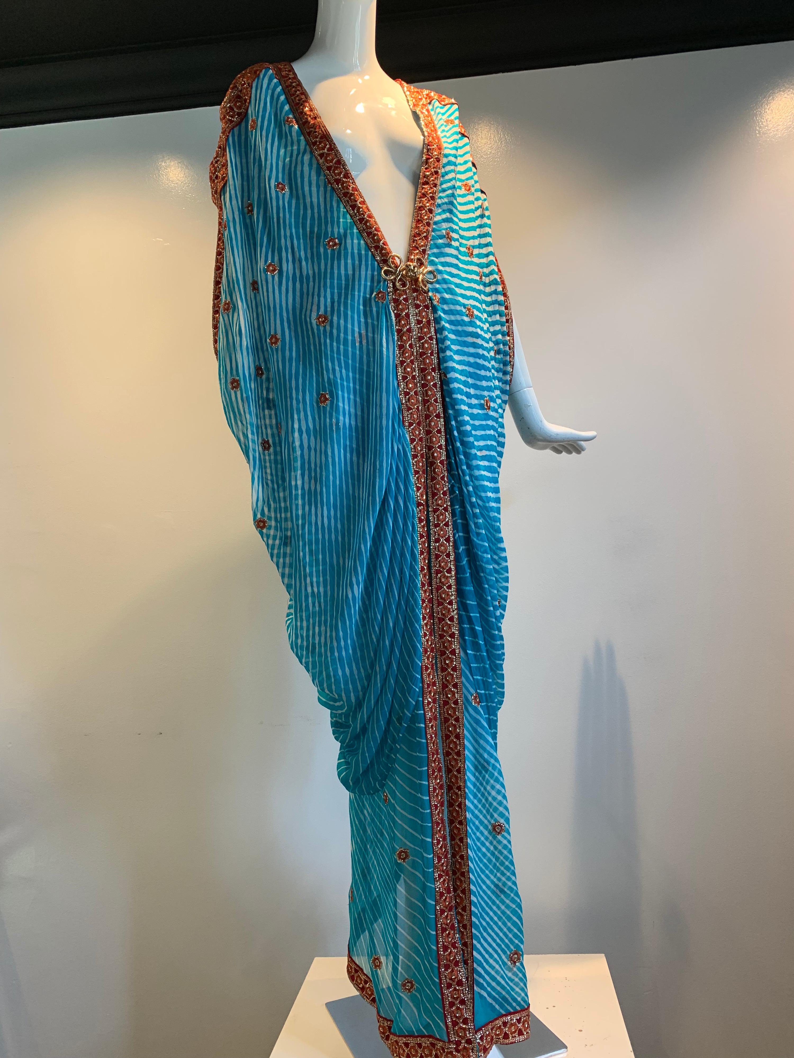 A stunning Torso Creations caftan made from exquisite vintage silk sari cloth of tie-dyed turquoise with rust and metallic thread embroidered stars and edging. Dolman effect draped sleeves and a back center adjustable drawstring for ease of