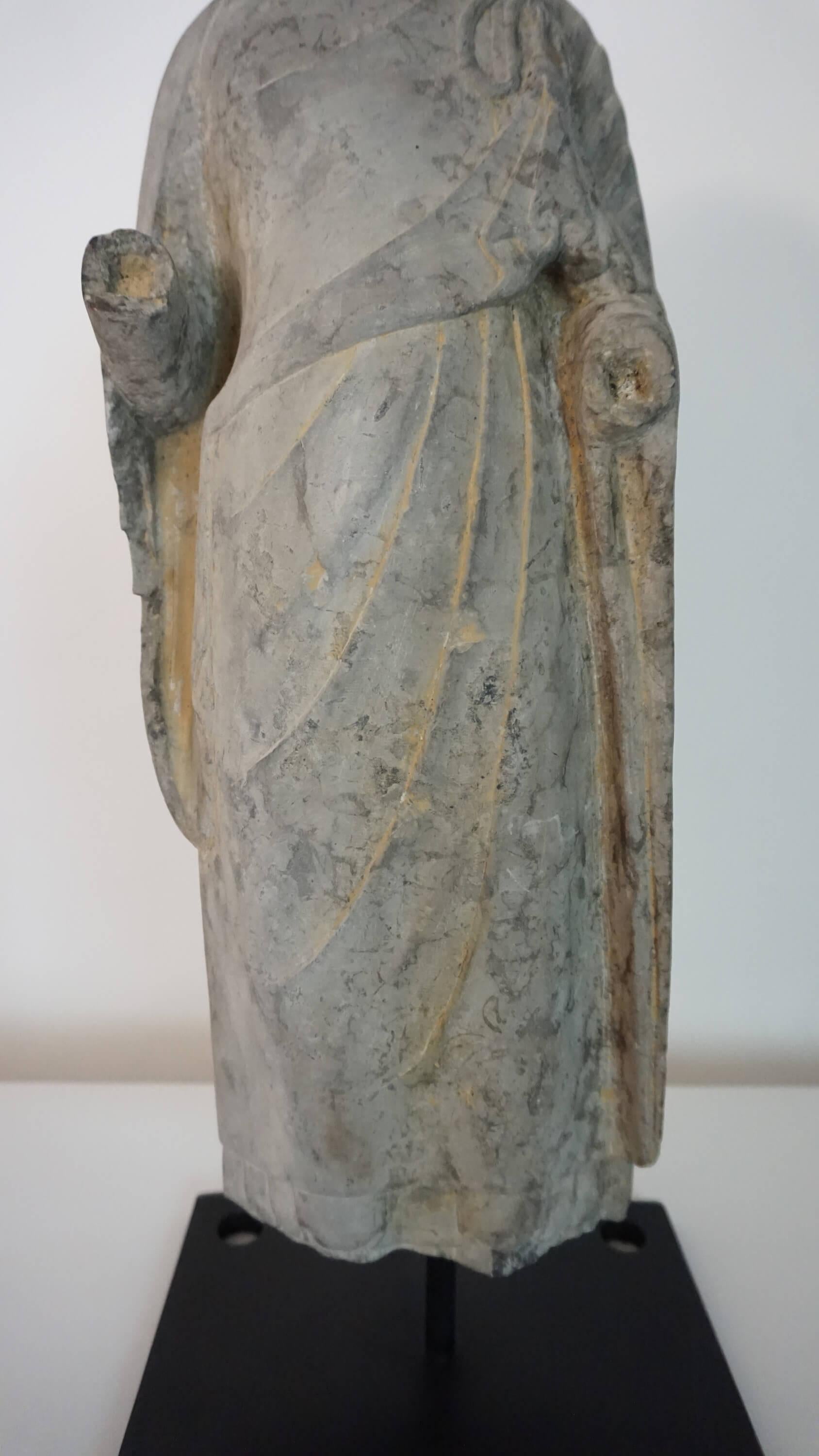 Chinese late Northern Qi to early Sui Dynasties (570-600 AD) carved gray limestone torso of the Buddha. Appearing very much like ancient classical Western sculpture, the Buddha stands in a vertical posture and dressed in monastic robes (kasaya) with