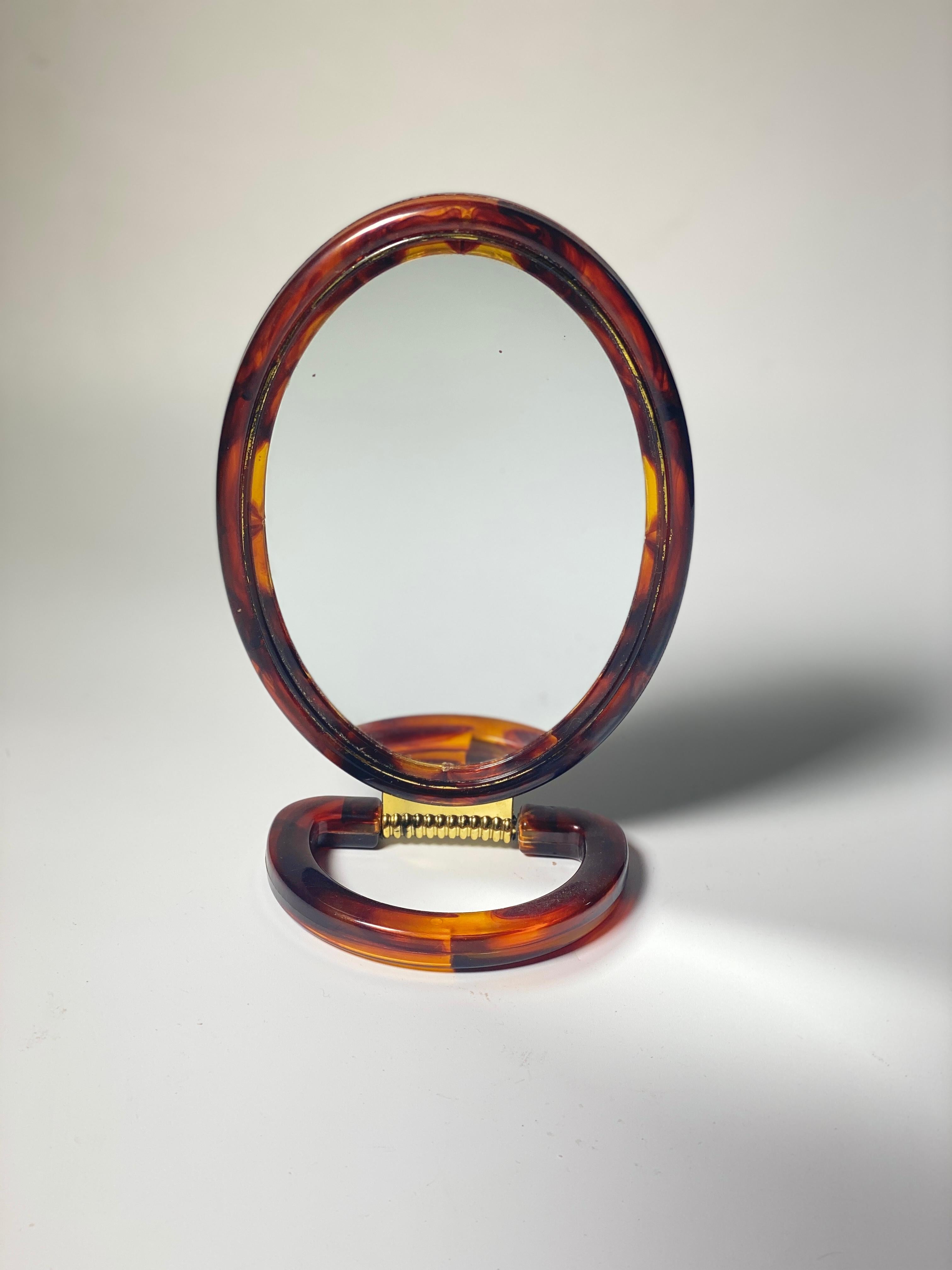 Dieser Spiegel ist ein Tischspiegel, ein Handspiegel. Aus schildpattähnlichem Kunststoff. Doppelseitiger Spiegel. Es wurde um 1970 in Frankreich hergestellt.