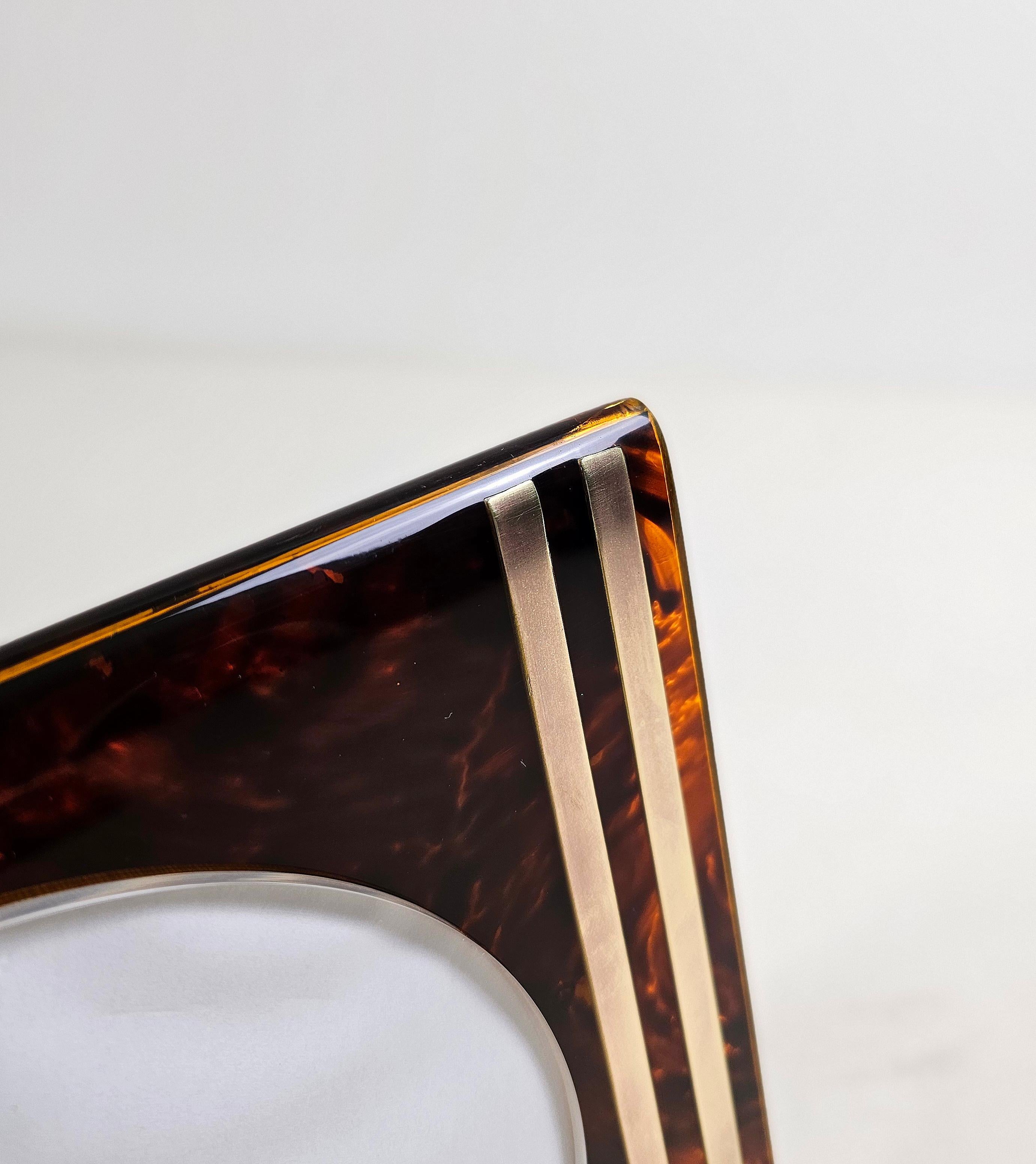 Cadre rectangulaire en lucite et laiton conçu et produit en Italie par l'équipe Guzzini. Le matériau Lucite, un type de résine acrylique connu pour sa transparence, historiquement utilisé pour les objets de luxe... Des motifs tachetés de brun et de