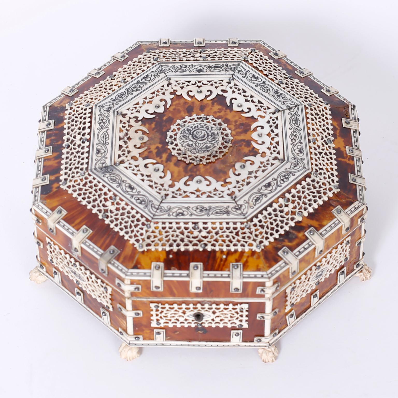 Antique Anglo-Indian octagon shaped jewelry or decorative box clad in tortoiseshell and elaborately decorated with carved bone. The inside has a mirror and felt lining.