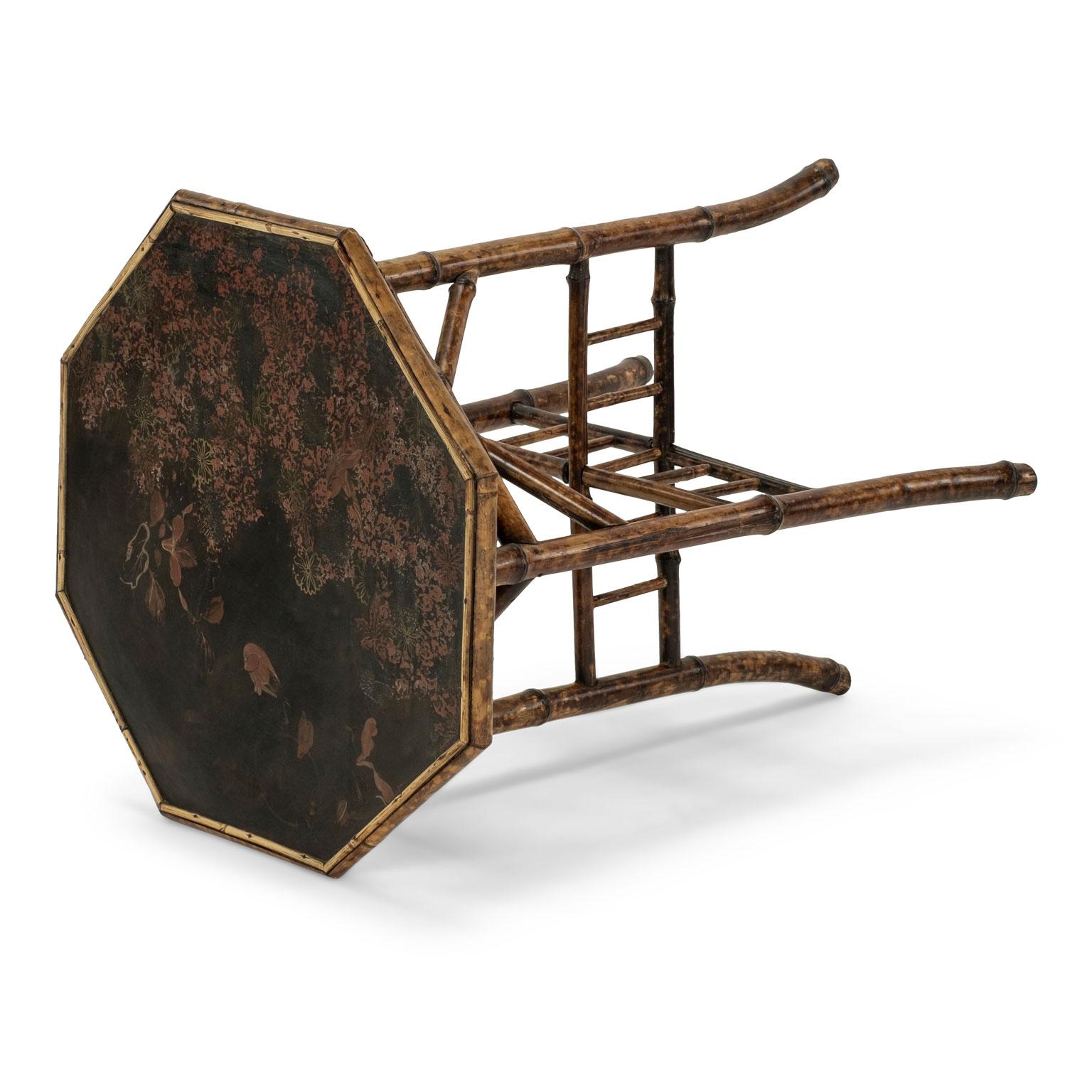 Tortoise shell bamboo side table: bamboo base supporting octagonal shape top adorned by Japanned lacquer scenes of birds, foliage and blossoms tinted in oxblood red on black.