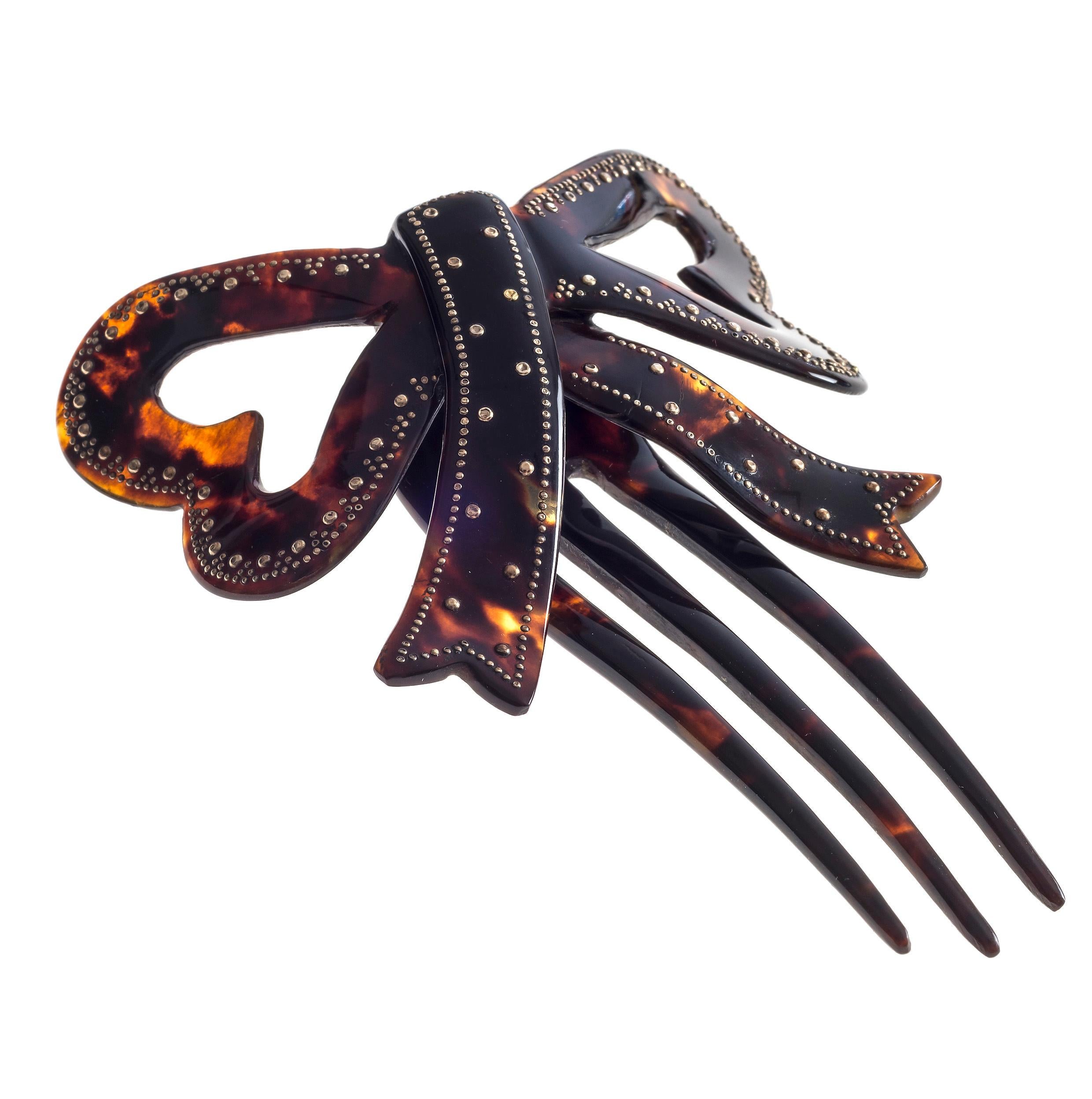 Highly unusual hair comb in the shape of bow. The finely carved tortoise shell bow is decorated with gold piqué work. The bow is attached to the comb with the help of a tortoise shell hinge. Fine work dating from 1860-1870.

size bow: 7,7 cm (W) x