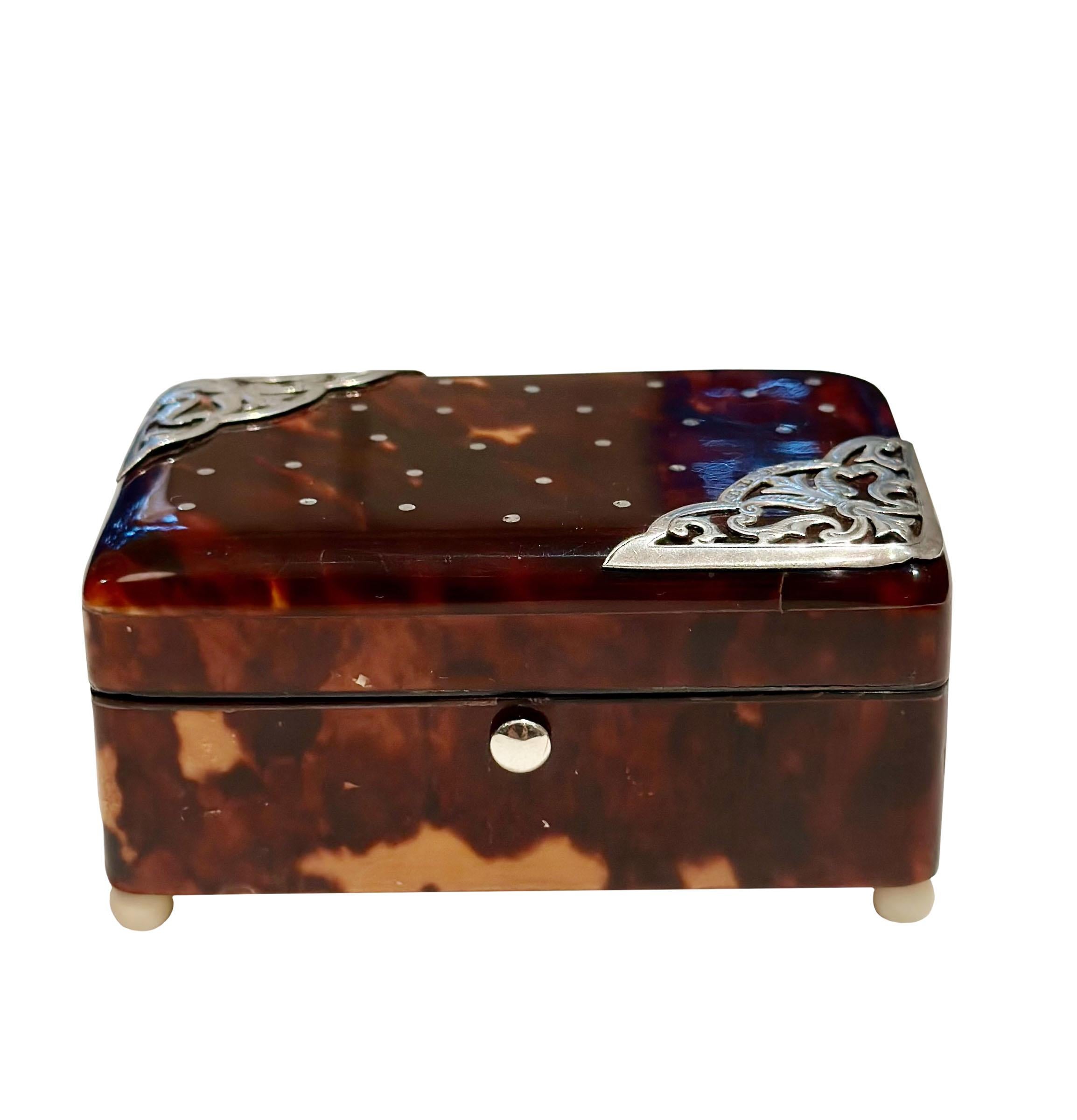 A very attractive tortoiseshell box with silver, on ivory ball feet. English hallmarks on sterling, circa 1880s. The interior has two compartments.