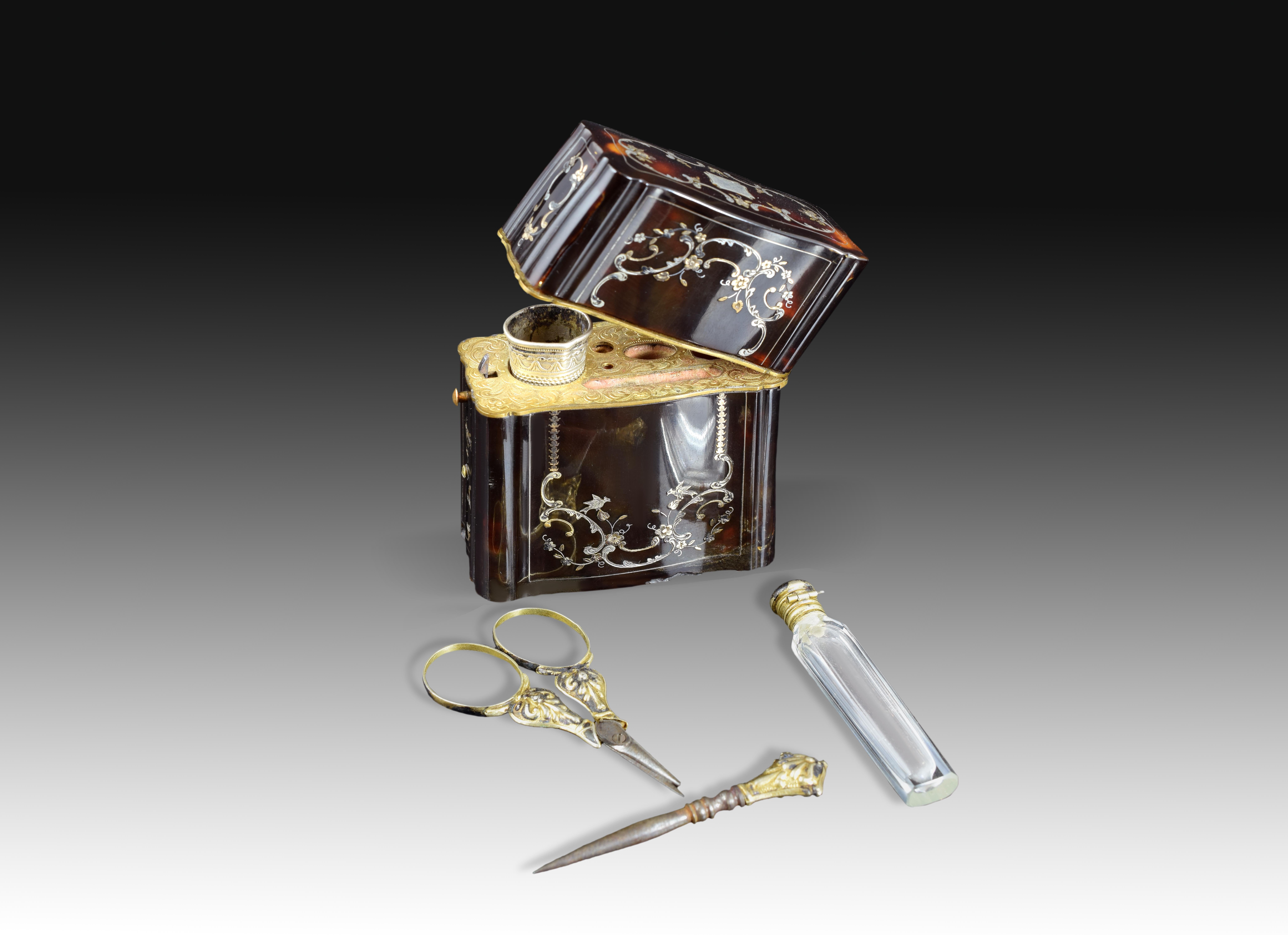 Rectangular case with hinged lid made decorated with fine inlays of floral and floral elements on its faces, containing a set of toiletry set composed of various elements of grooming and personal use (a small bottle of perfumes, scissors, a thimble