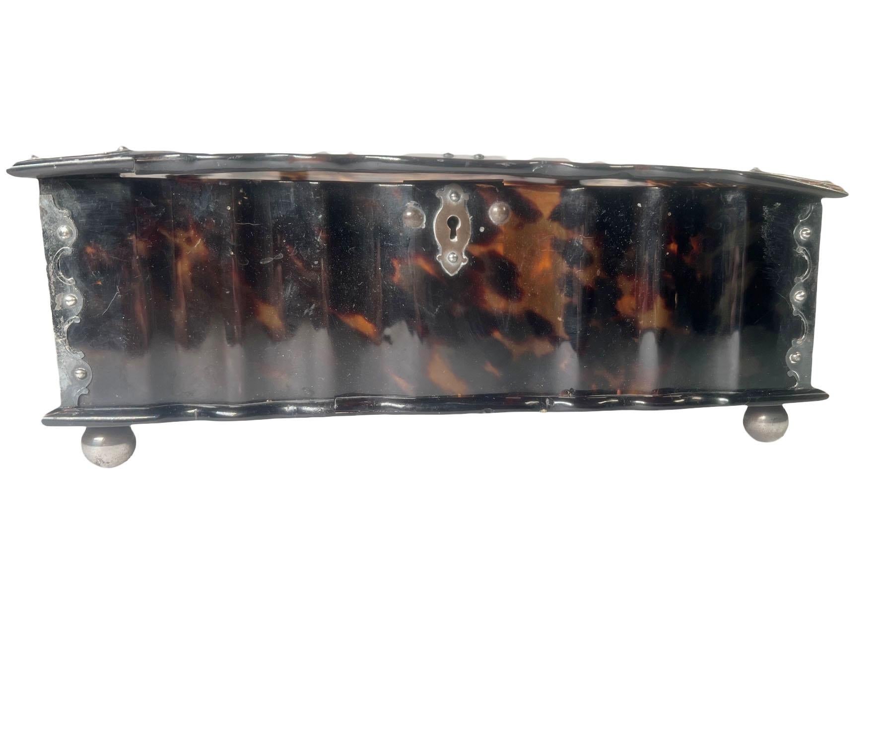 Rara caja holandesa del siglo XVIII de carey con laterales ondulados en forma de serpiente, adornada con monturas de plata y pies de bola de plata de movilidad. Algunas pequeñas grietas en la tapa, apenas perceptibles. Hacia 1780-1820.