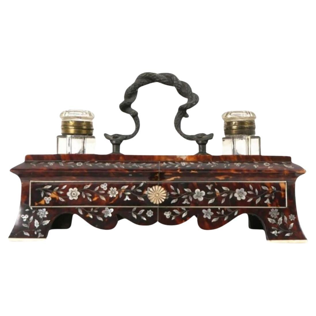 An exquisite blend of elegance and functionality, this tortoiseshell double inkwell is a true collector's delight. With its stunning glass inkwells, brass accents, and convenient storage drawer, it's a timeless piece that adds a touch of