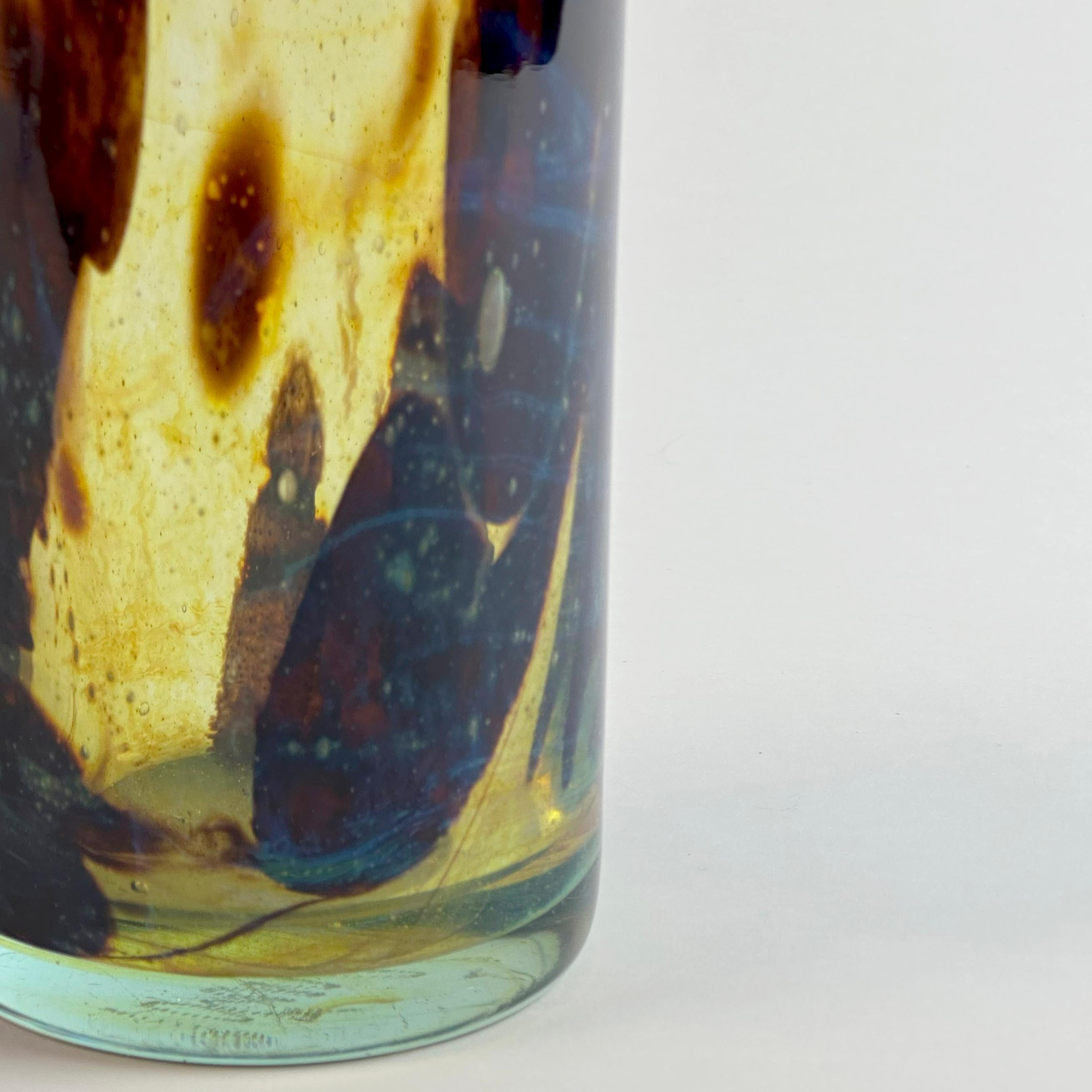 Un vaso a bottiglia in vetro alto e caratteristico, realizzato a mano da Mdina Glass sull'isola mediterranea di Malta a metà degli anni Settanta. 

Il vetro è lavorato in toni ricchi e organici di marrone intenso e giallo ocra, producendo un effetto