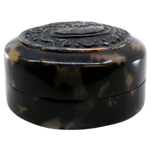 Tortoiseshell pill box with embossed silver application on the removable lid
