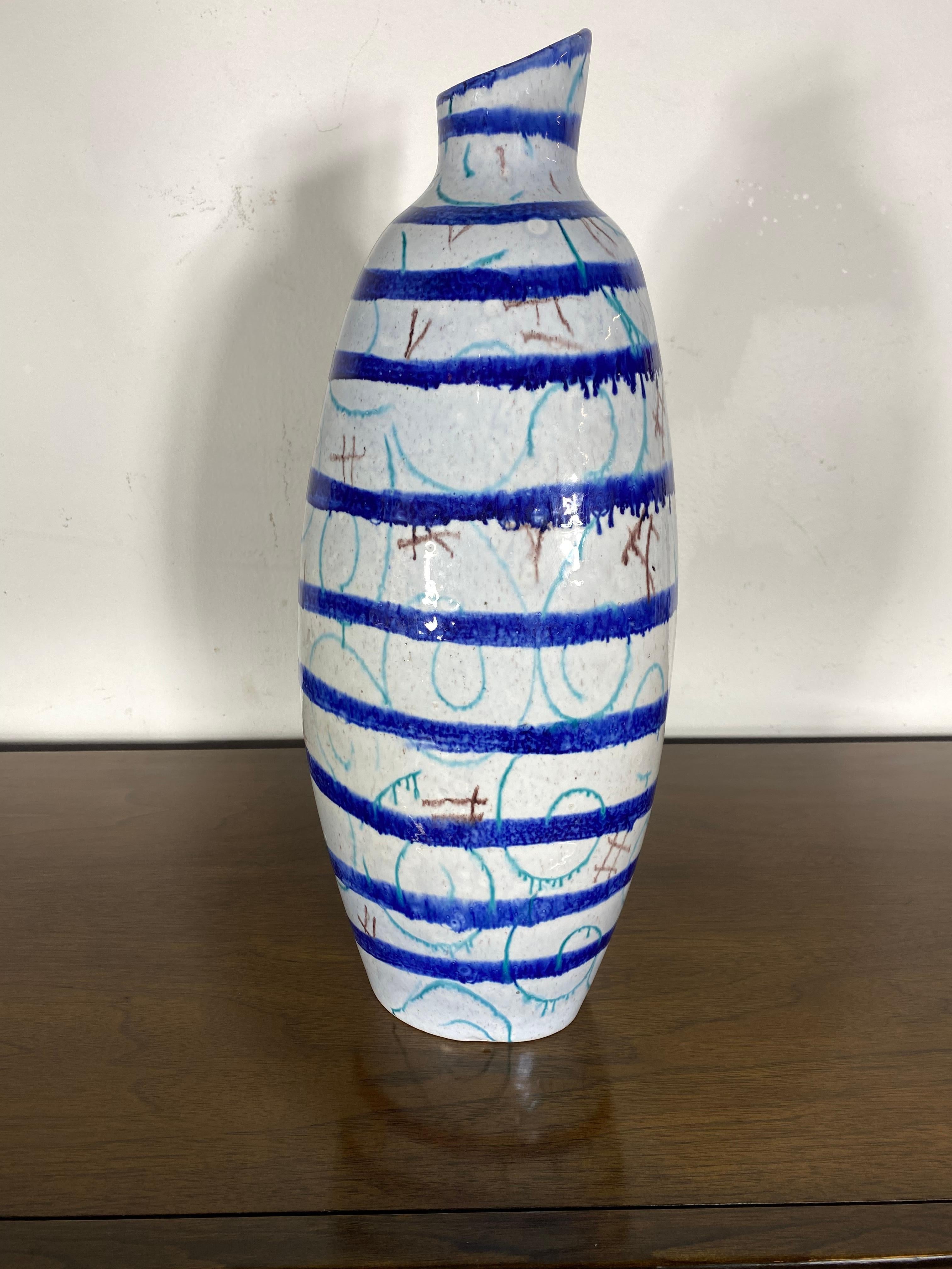 Bottiglia in ceramica fatta a mano da Torviscosa. Forma irregolare della bottiglia con bocca tagliata obliquamente nella parte superiore. Gli smalti a fuoco vivo in verde e blu screziato creano un bellissimo effetto. Un ottimo esempio di ceramica