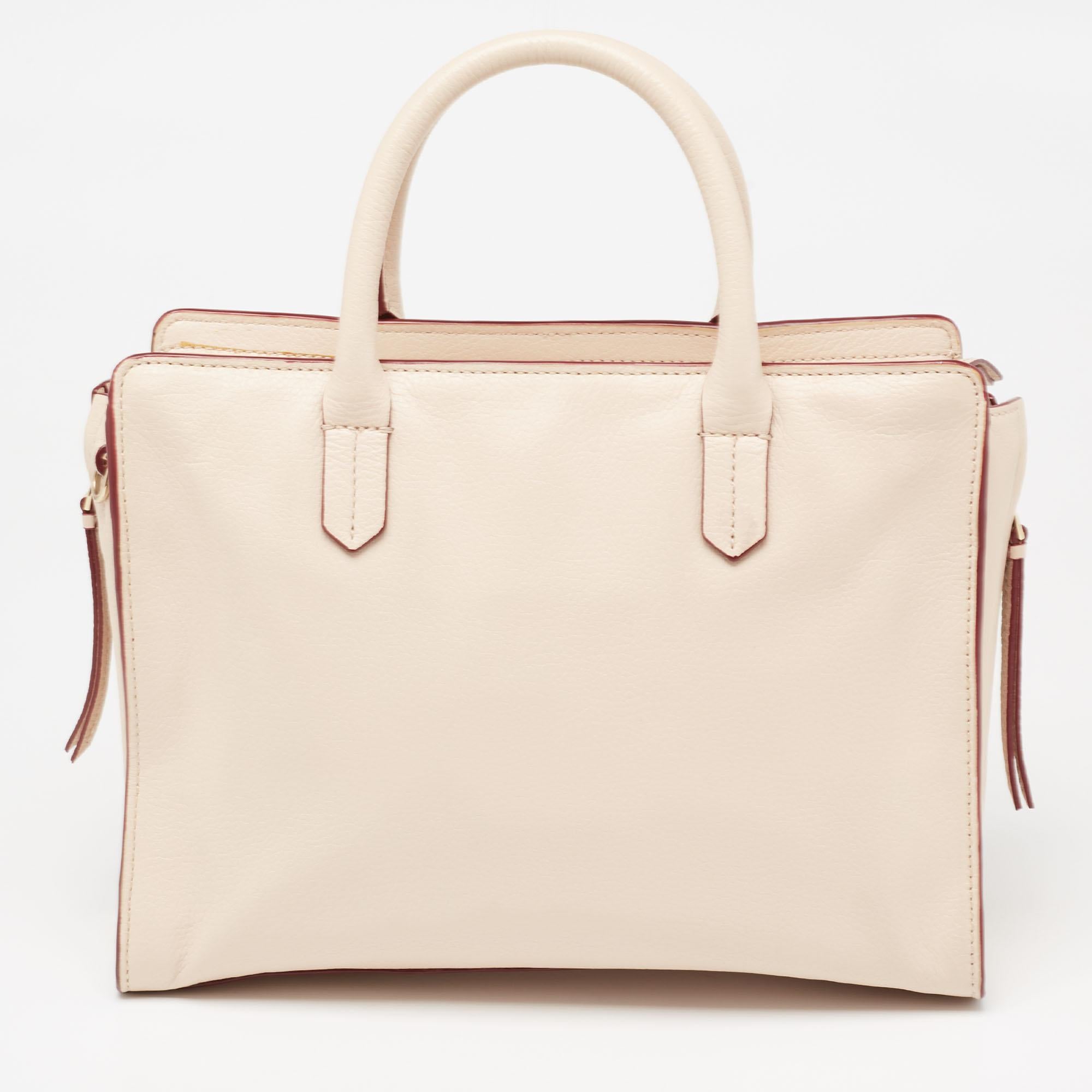 This timeless Robinson tote is from Tory Burch. It carries a beige-hued exterior made of quality leather and it has been equipped with two top handles, a shoulder strap, and a spacious fabric interior. The tote is ideal for everyday use.

Includes: