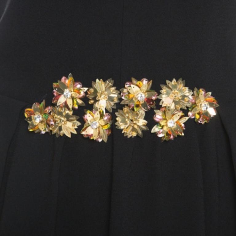 Tory Burch a conçu cette élégante tenue de soirée avec de subtiles touches de glamour. Cette robe noire sans manches présente un corsage noir uni et un bas plein. Elle est ornée de perles, de paillettes et de cristaux au niveau de la taille. Elle