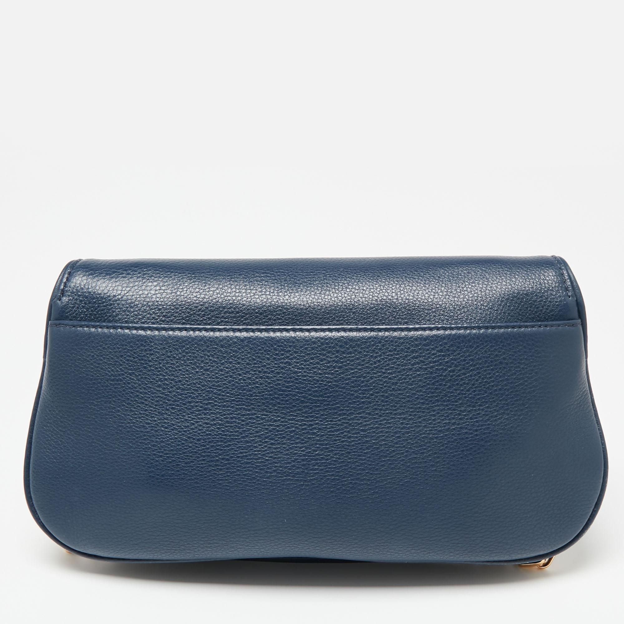 This crossbody bag from Tory Burch is crafted from blue leather and held by an adjustable shoulder strap. The Britten bag features the brand's iconic logo on the front flap and the brand plaque inside the nylon interior.

