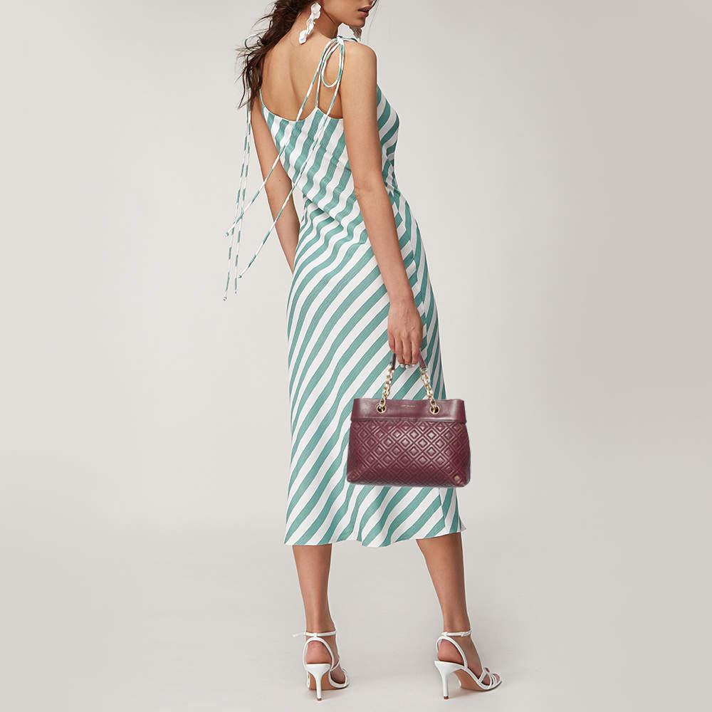 This Fleming satchel from Tory Burch has been meticulously crafted from leather in a classy burgundy and designed with quilts in diamond patterns and the label on the front. The top opens to a fabric-lined interior and the bag is held by two