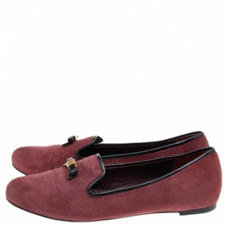 Diese Smoking-Slipper von Tory Burch sind der Inbegriff von klassischer Coolness. Das aus Wildleder gefertigte Paar hat einen niedrigen Absatz, eine runde Schuhspitze und ist einfach zum Hineinschlüpfen. Die goldfarbenen Schleifen mit Markendetails