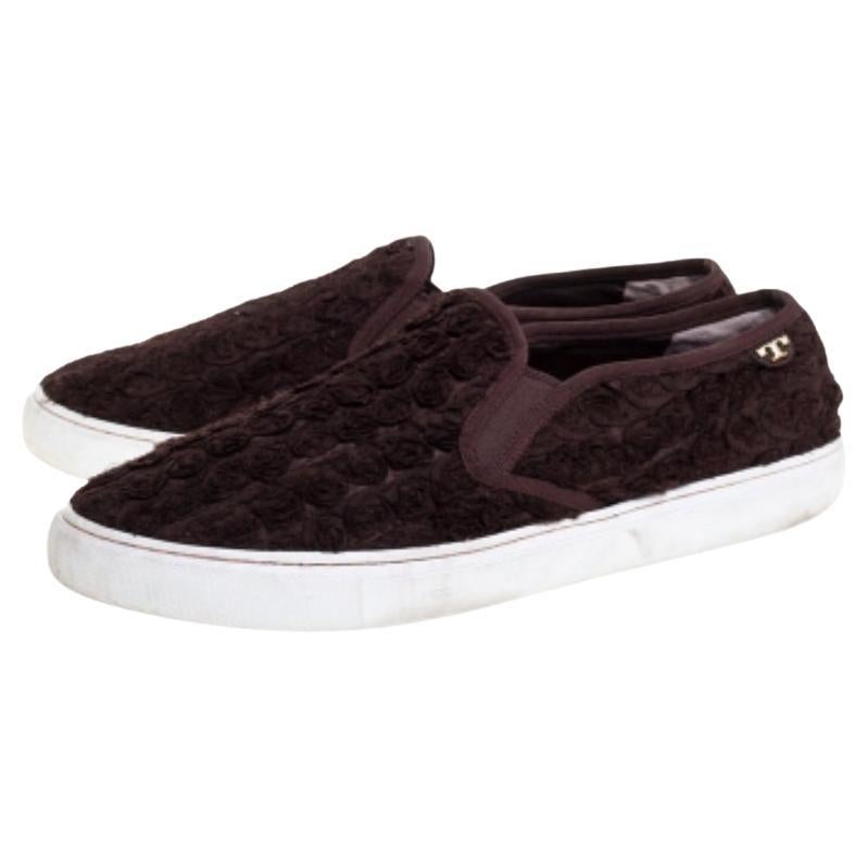 These stylish slip-on sneakers by Tory Burch are perfect for everyday use and casual outings. Crafted from quality fabric, these dark brown sneakers flaunt small rosettes on the exterior. With the brand detail in gold-tone, leather lining, insoles
