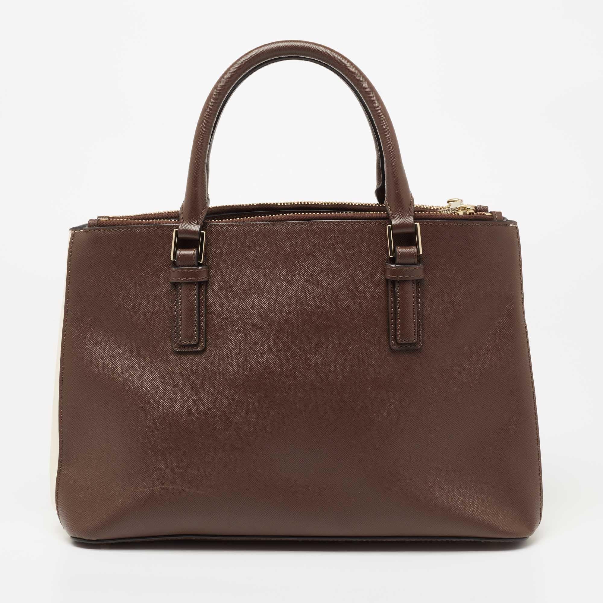 This luxurious Robinson Double Zip tote from Tory Burch will surely meet all your handbag expectations! It is made from dark brown and white Saffiano leather and flaunts a logo accent on the front. It has a chic silhouette that is supported by dual