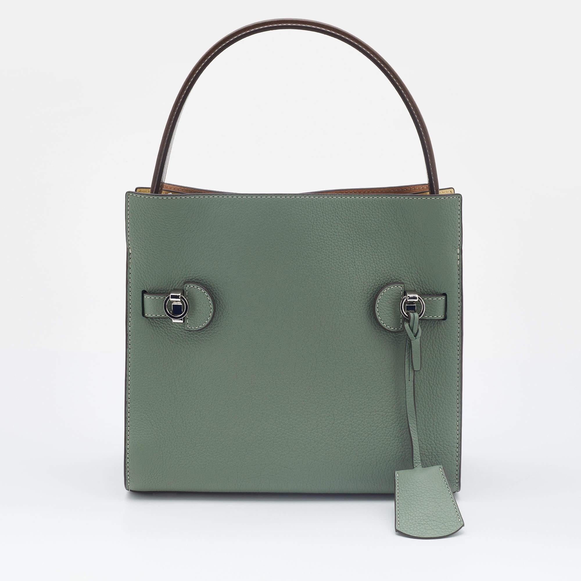 The Lee Radziwill bag is named after a woman admired by Tory. This here is constructed using leather-suede and fitted with a signature lock in silver-tone hardware. A shapely handle is attached to the top and an optional shoulder strap is offered