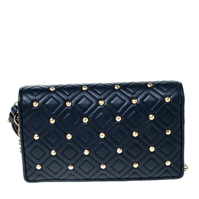 This Fleming bag from Tory Burch has been meticulously crafted from leather in navy blue and designed with quilts in diamond patterns and gold-tone studs. The flap opens to a leather and fabric-lined interior and the bag is held by a leather