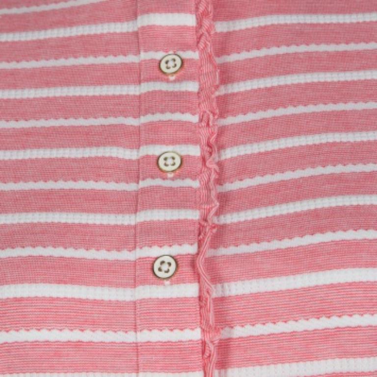 Esta creación de Tory Burch presenta un estampado de rayas rosas y blancas y detalles de volantes a lo largo de los botones delanteros y el cuello alto que añaden un toque femenino a la parte superior, convirtiéndola en una bonita prenda para lucir