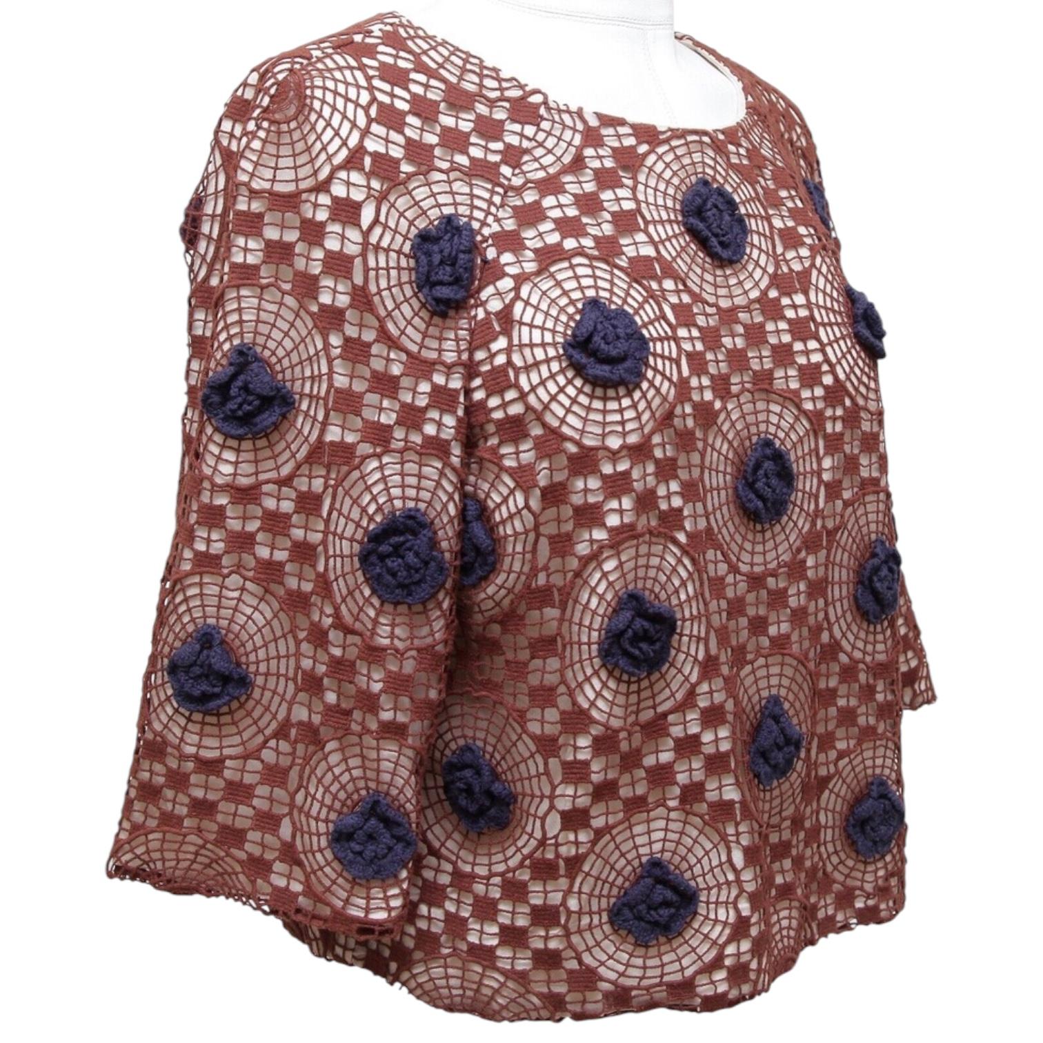 GUARANTEED AUTHENTIC TORY BURCH FLORAL CROCHET KNIT BLOUSE

Design:
- 3/4 sleeve crocheted knit blouse in a brown and navy blue color.
- Crew neckline.
- Slip on, rear button closure at neckline.
- Ivory attached slip.

Material: 100% Cotton; Lining