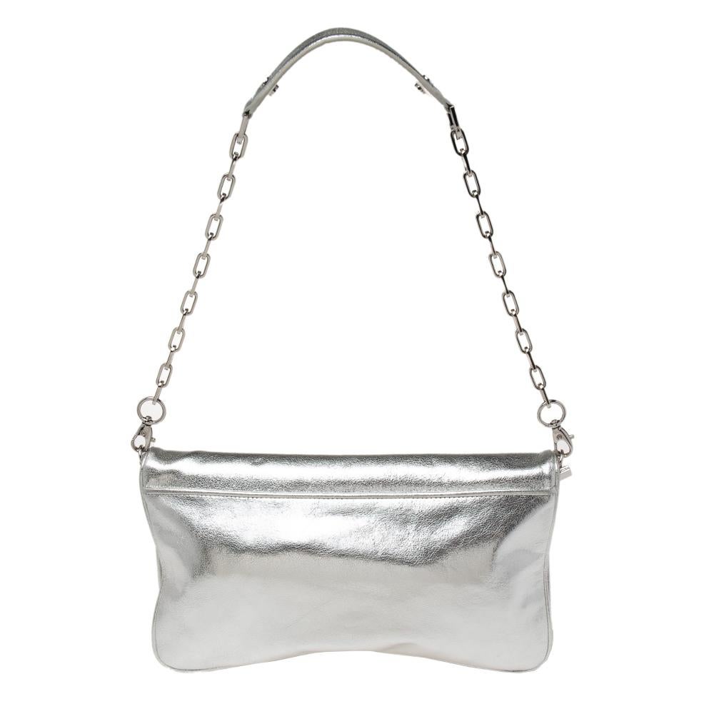 This Tory Burch clutch is crafted from silver leather and highlighted by the brand logo at the front. It has a shoulder chain and a flap closure that opens to a fabric-lined interior.

