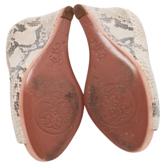 This pair of Tory Burch pumps will be a valuable addition to your closet. Created from python-embossed leather and suede, the wedge heels of this pair is supported on platforms for a smooth walk.