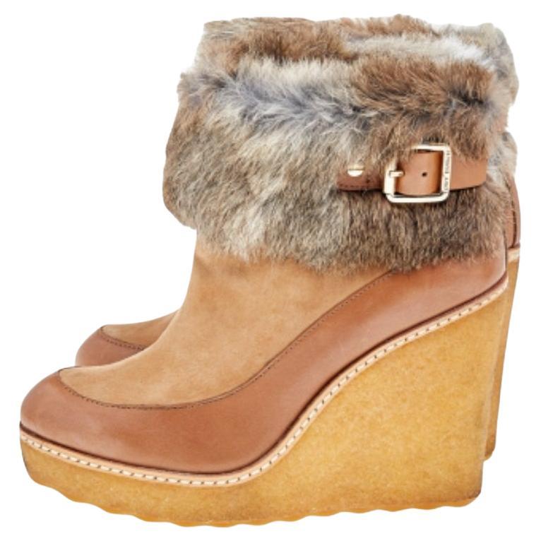 Comfort and fashion join hands in these lovely boots from Tory Burch. These tan ankle boots are crafted from leather and suede and feature round toes, fur trims on the ankles, leather-lined insoles, and 11 cm wedge heels.