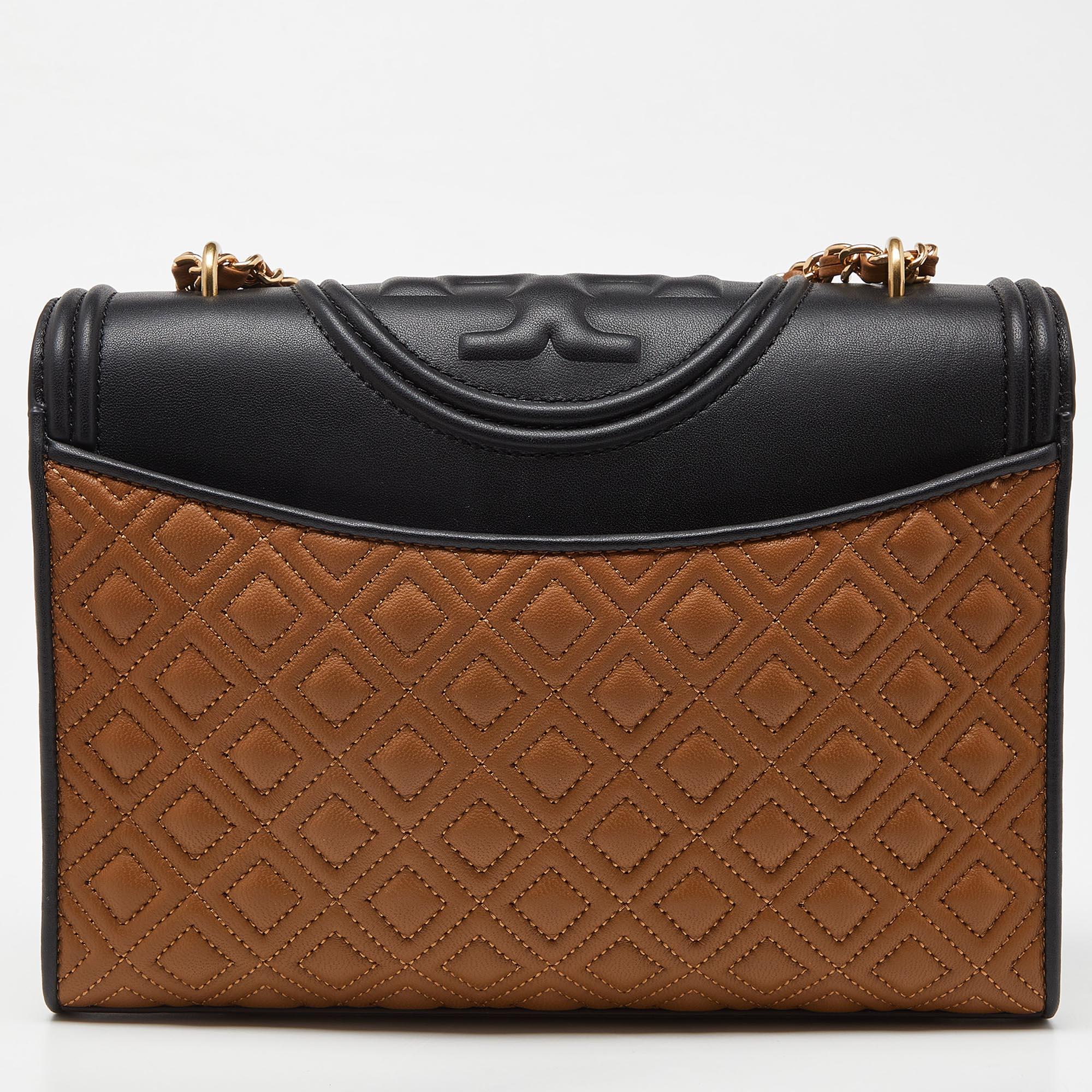 This Fleming shoulder bag from Tory Burch has been meticulously crafted from leather and designed with quilts in diamond patterns and the logo on the top. The flap opens to a fabric-lined interior, and the bag is held by an interwoven chain