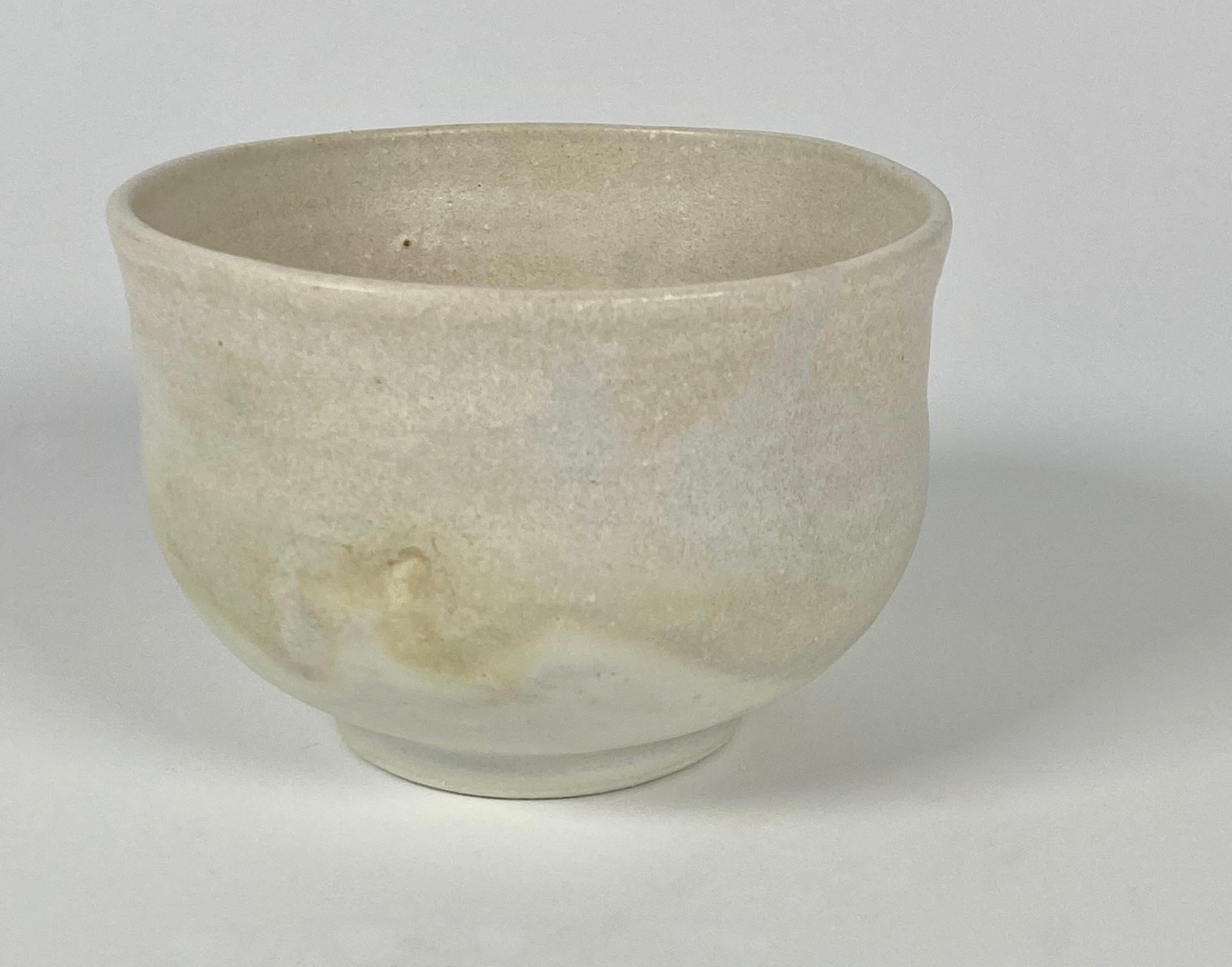 Ceramic tea bowl by artist Yoshiko Takaezu (1922-2011) layers of soft off white glazes in this subtle form. Takaezu was part of the Modernist ceramic artists who challenged the way ceramics were created. She explored the concept of the closed form
