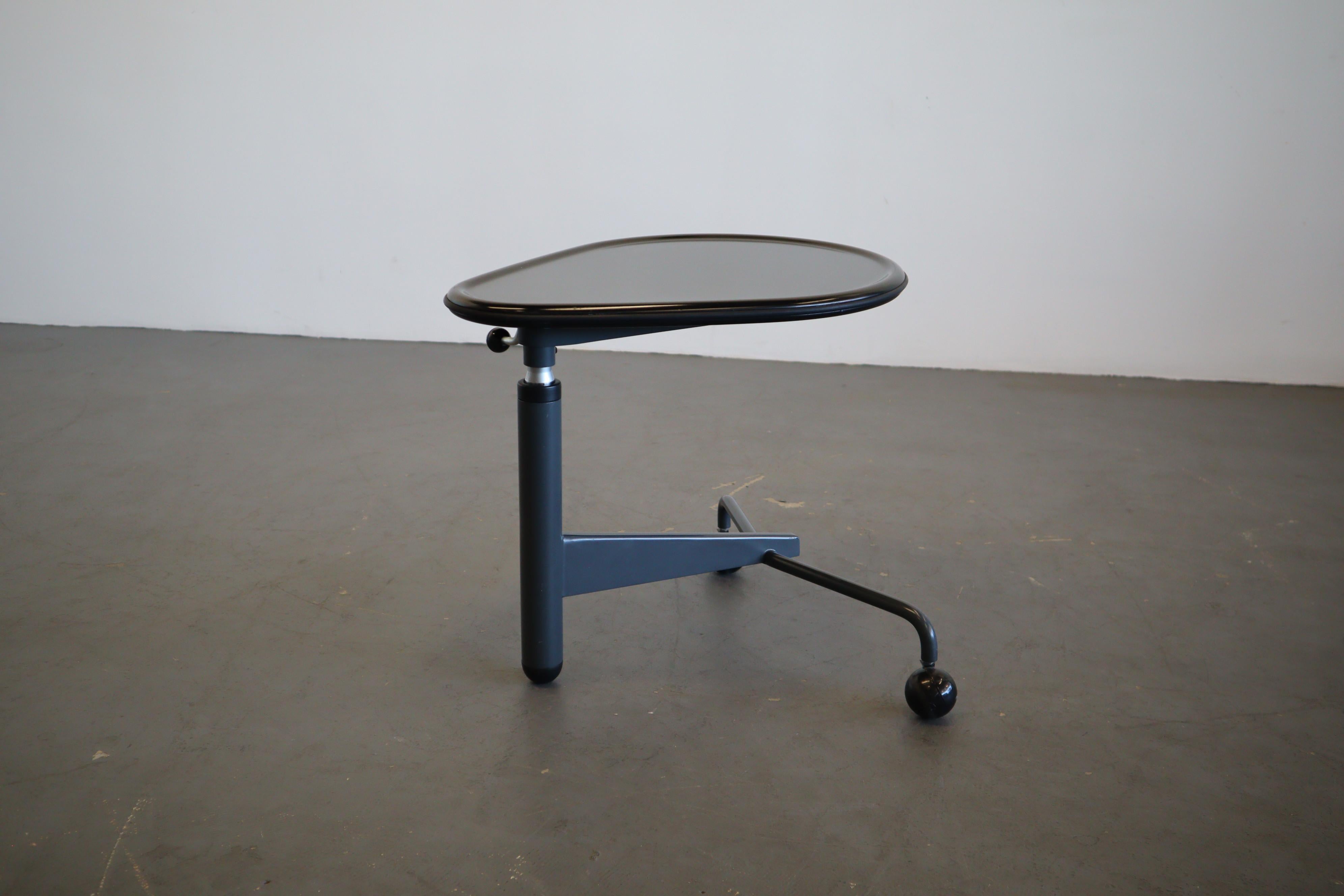 Adjustable height small side table by well known Japanese designer Toshiyuki Kita. This very unique design has the ability to compliment any style. It has a black lacquered composite top with a grey metal lower frame and plastic casters. This piece
