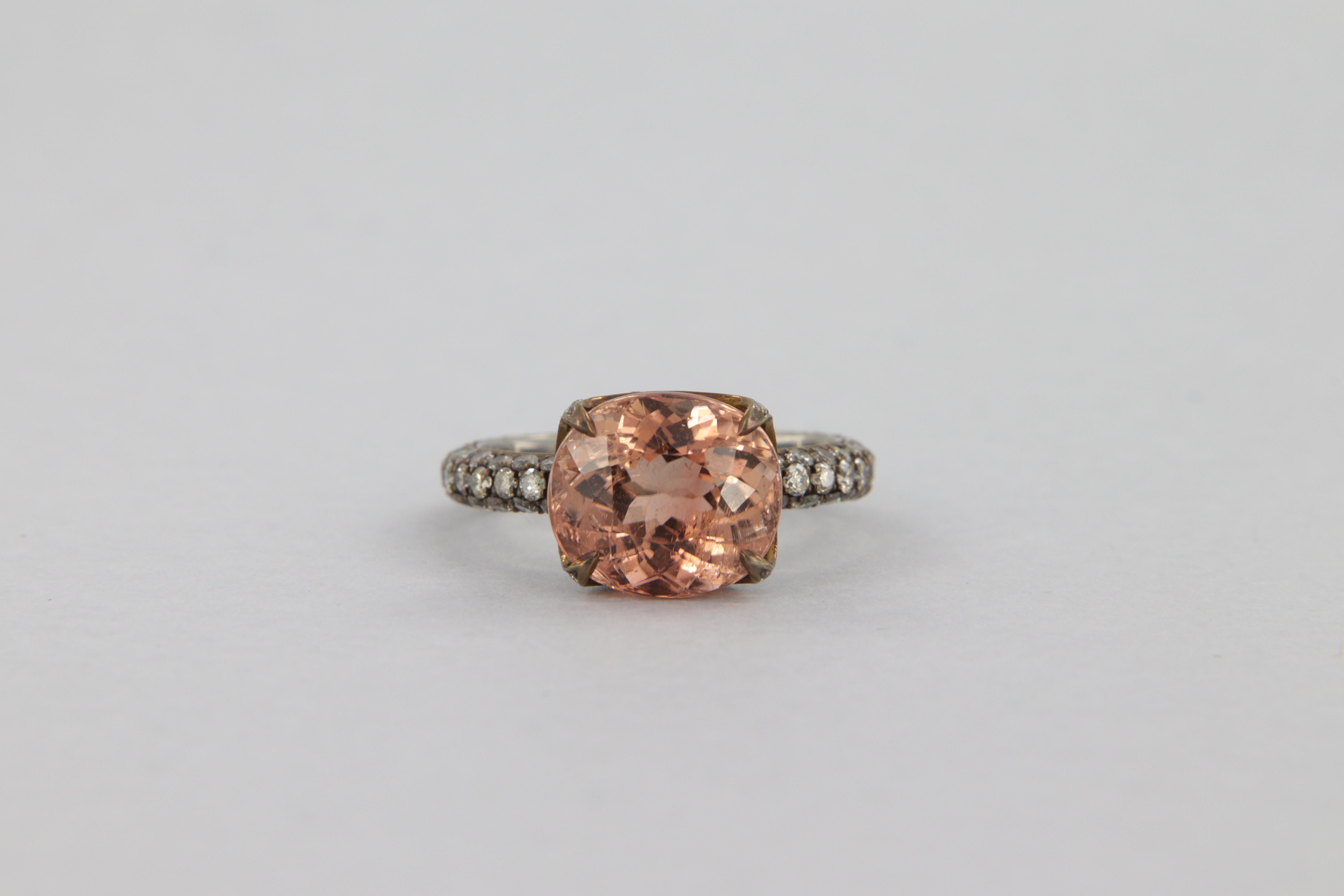 Ring made of titanium with oval orange pink tourmaline, weighing carats 4.99, decorated with small light brown diamonds with VS-SI clarity, round brilliant cut, with a total weight of carats 1.52

Titanium has been anodized in the brown bronze color