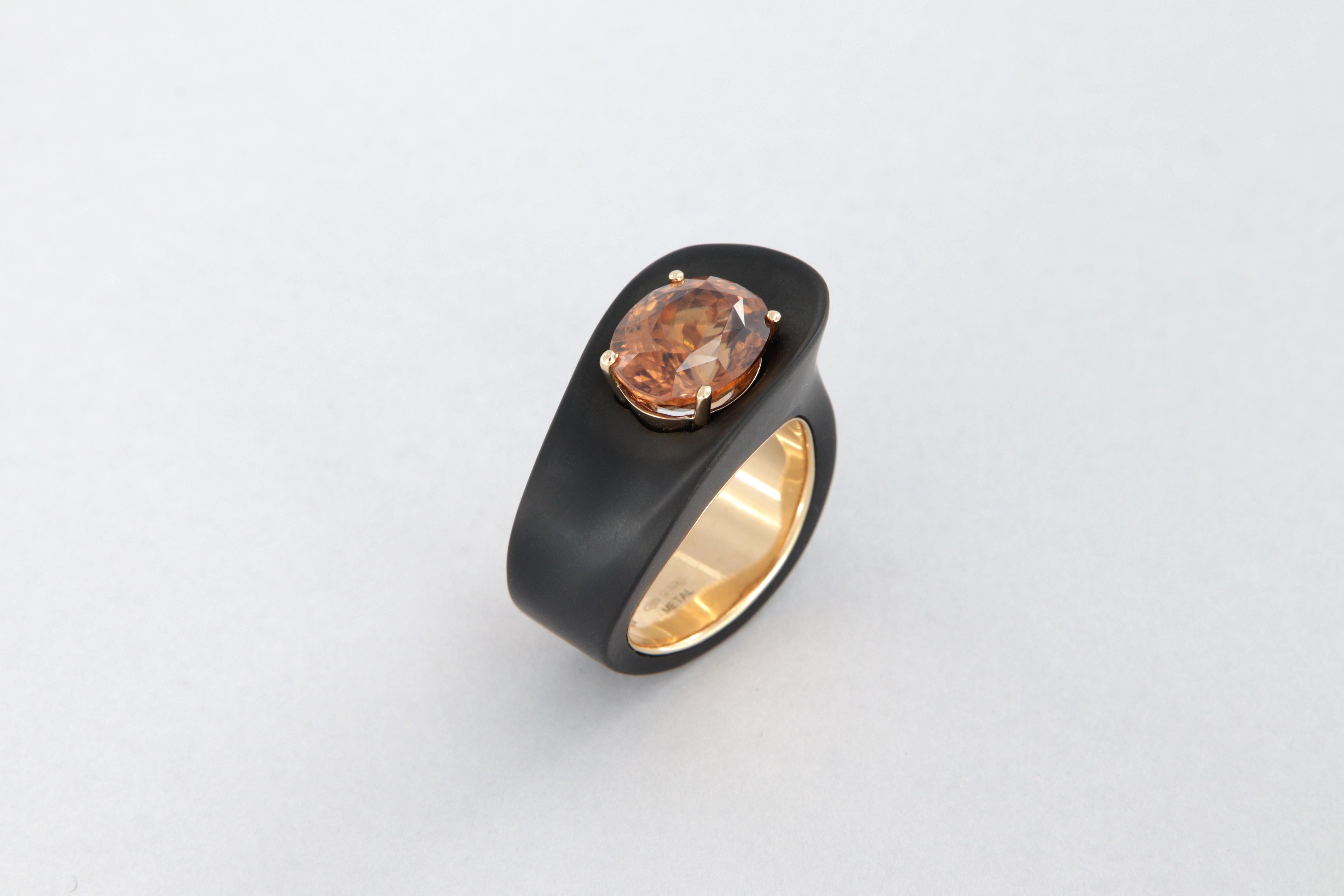 Bague avec zircon naturel orange-brun, ovale ct 7.14,  en or rose 18 carats et fer avec traitement DLC noir mat, poids total g 21,7.

Il s'agit d'une pièce unique, fabriquée en Italie,  la finition du fer en DLC  (Diamond Like Carbon) le noir mat
