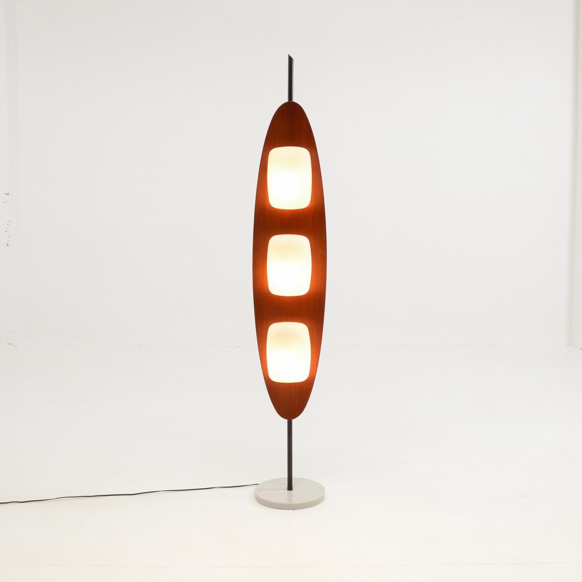 This Mid-Century Modern floor lamp was designed by Goffredo Reggiani and manufactured by Studio Reggiani in Italy.
This lamp features a white marble base, a black lacquered tubular stem with a teak moulded plywood shade and 3 opaline glass