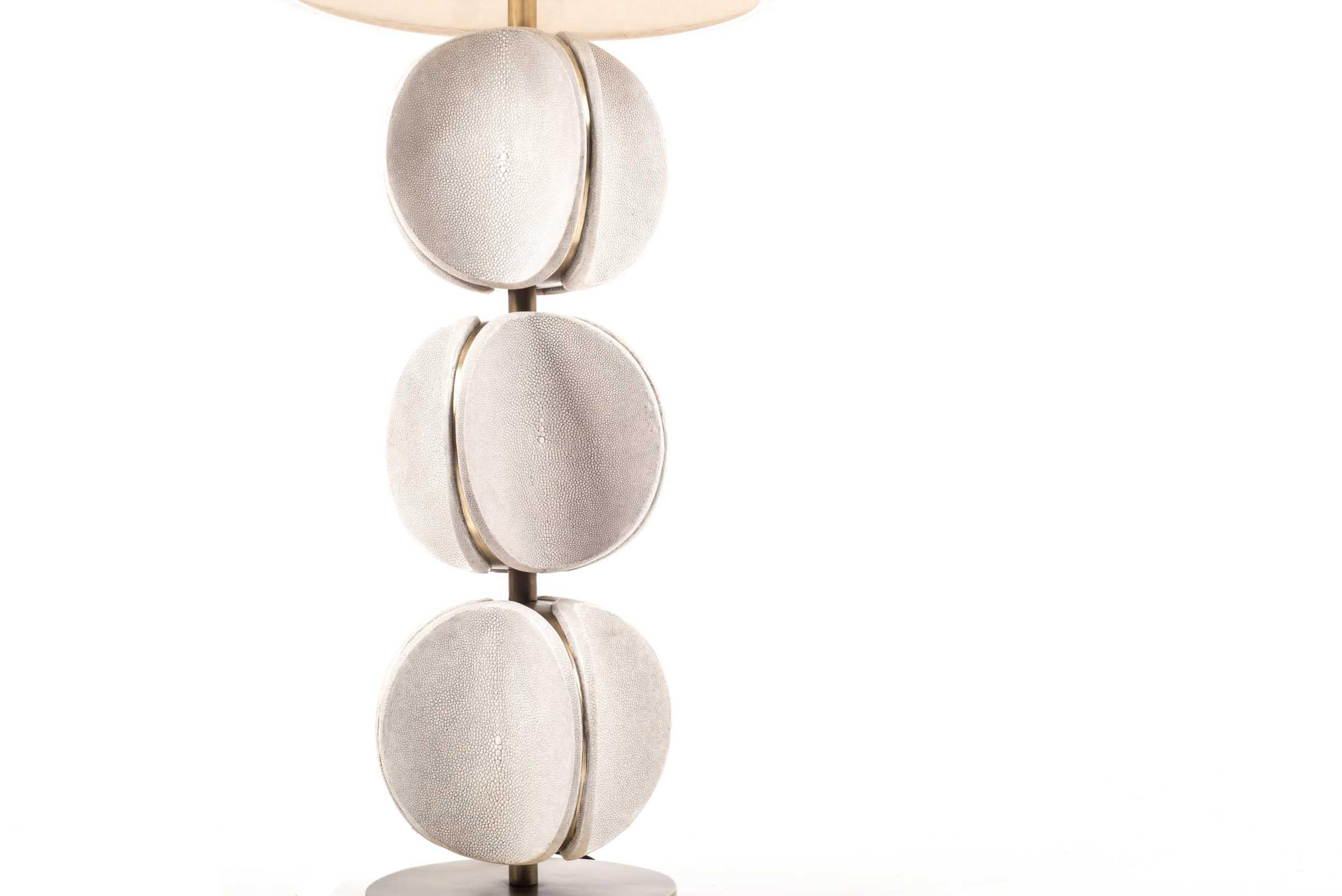 The TOTEM Lamp in cream shagreen is a playful piece with it's rotating parts. These modern TOTEM-inspired parts that concave, have subtle bronze-patina brass details that frame each part. This piece makes for a chic table table. This piece is