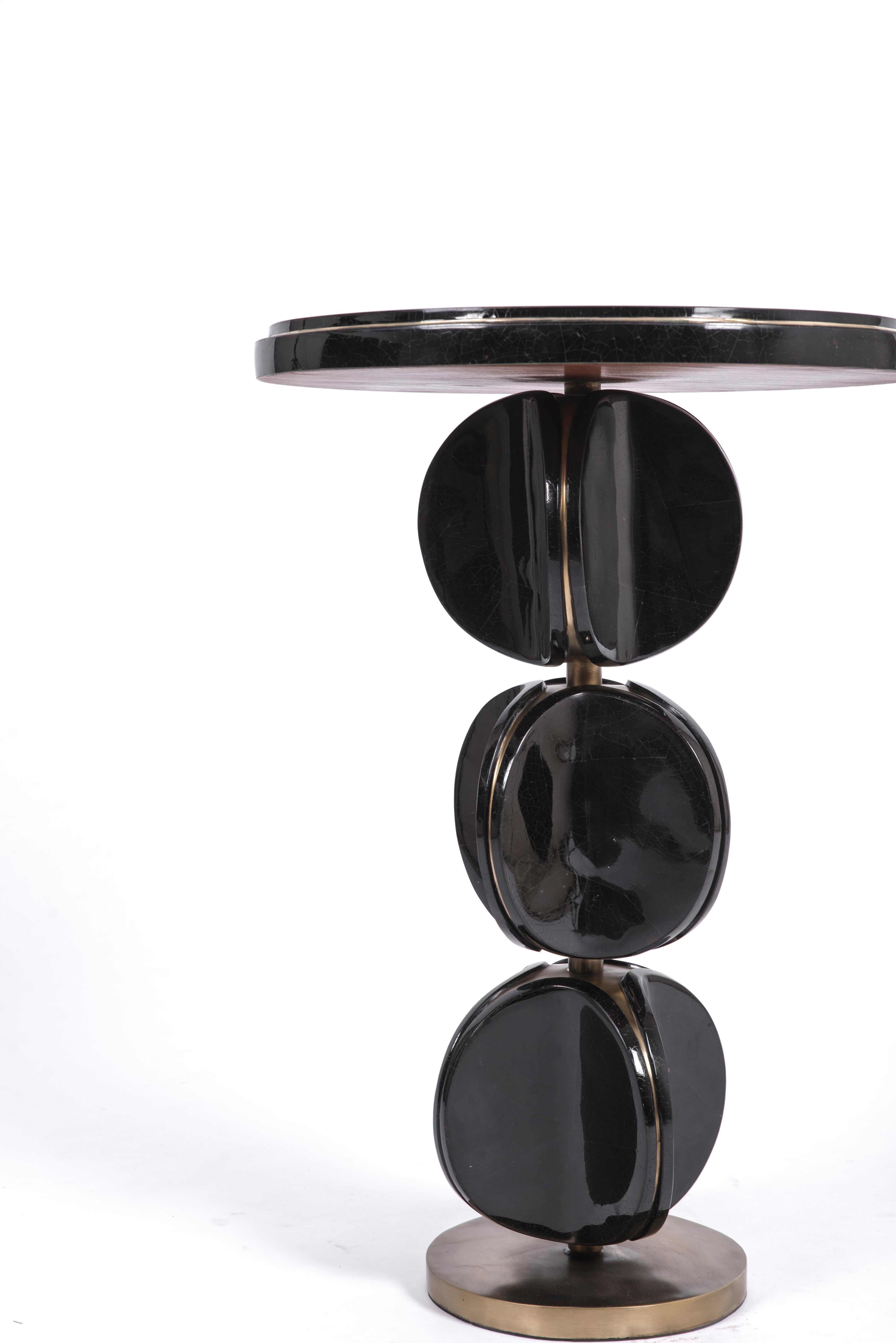 The TOTEM side table in black pen shell is a playful piece with its rotating parts. These modern TOTEM-inspired parts that concave, have subtle bronze-patina brass details that frame each part. This piece makes for a chic end table. This piece is