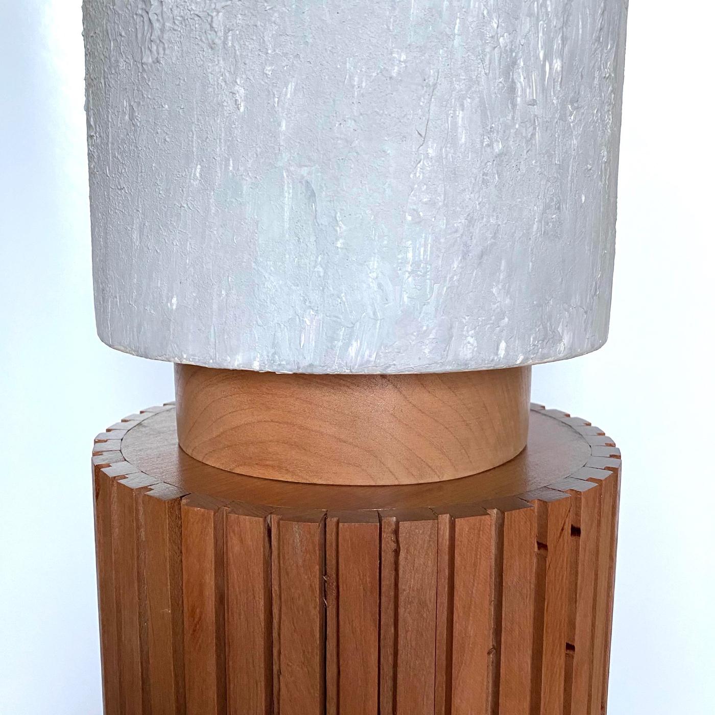 Inspired by the imposing, fierce silhouette of totem poles, this one-off table lamp is comprised of an interplay of cylindrical volumes of high visual impact even when the lamp is off. A round, deftly engraved base in solid durmast sustains the body