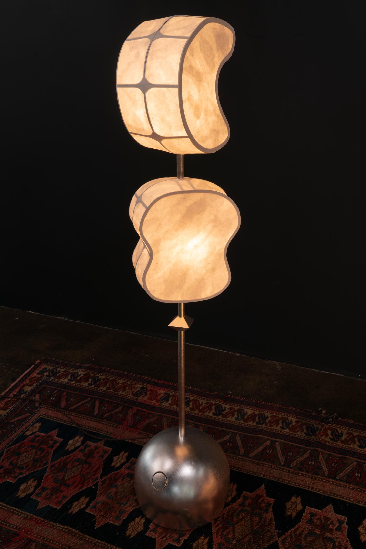 The Totemic Standing Lamp 2(1) is a standing lamp with 2 Hanji paper shades (Moon 10.5, Sage 10.5) and 1 diamond bead.  The item in stock comes in Natural Hanji paper shades and Silver Leaf on brass.

Totemic is Andrea Claire Studio’s latest