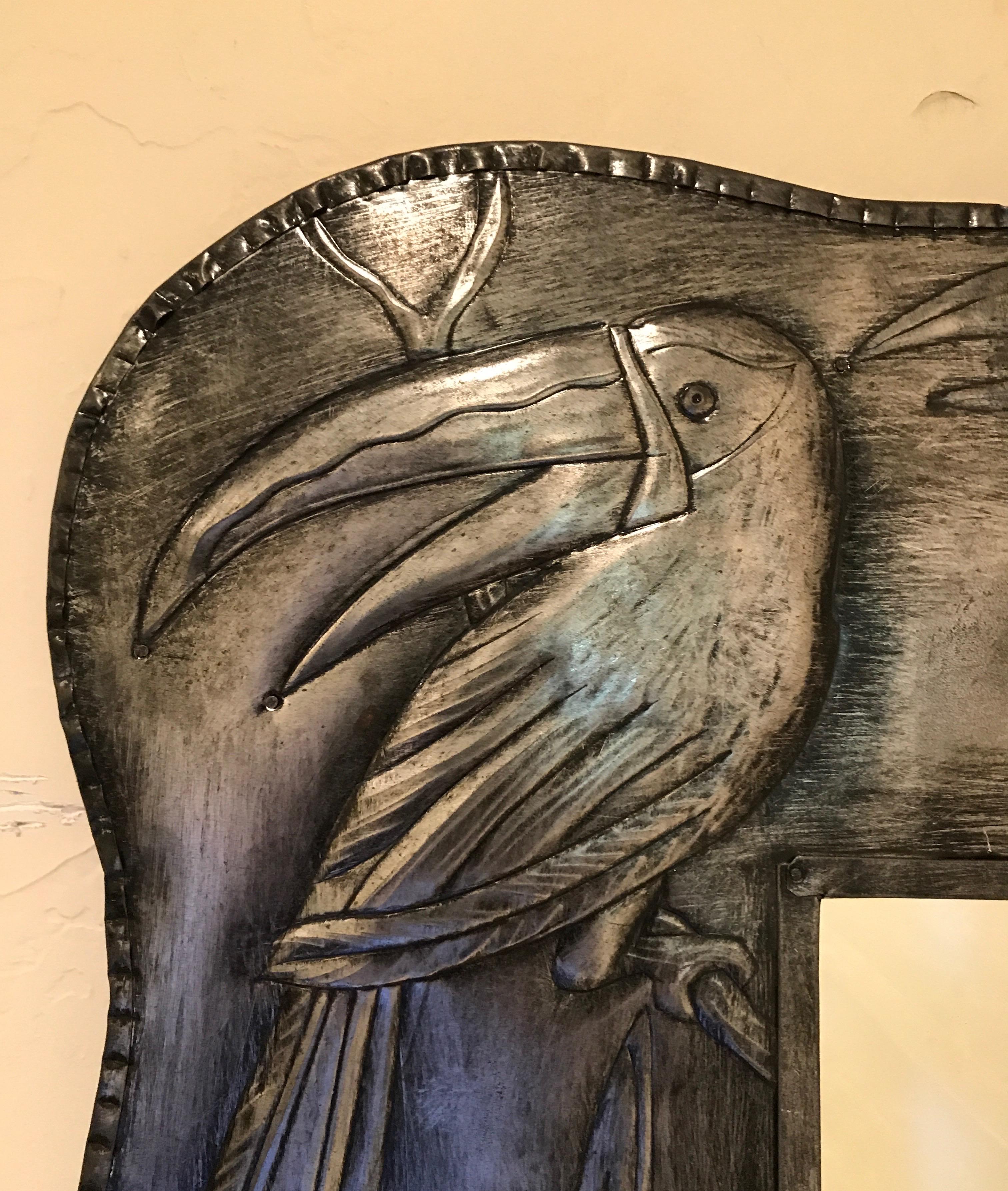 Metal framed mirror with embossed toucan motif.