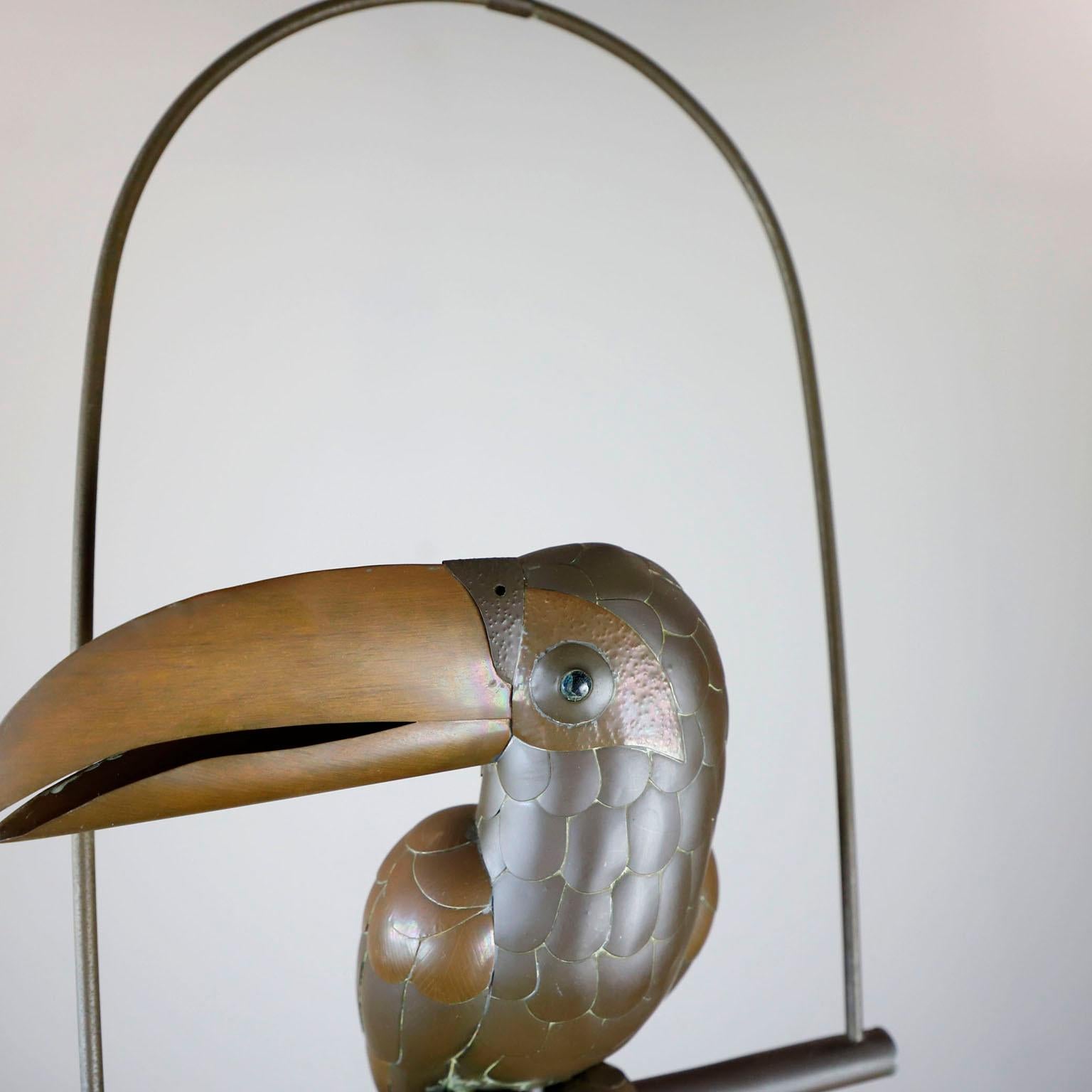 Tucano in rame e ottone su un supporto da appendere a cerchio di Sergio Bustamante, circa 1960. Ottime condizioni vintage.

Sergio Bustamante è un artista e scultore messicano. Ha iniziato con dipinti e figure di cartapesta, inaugurando la prima