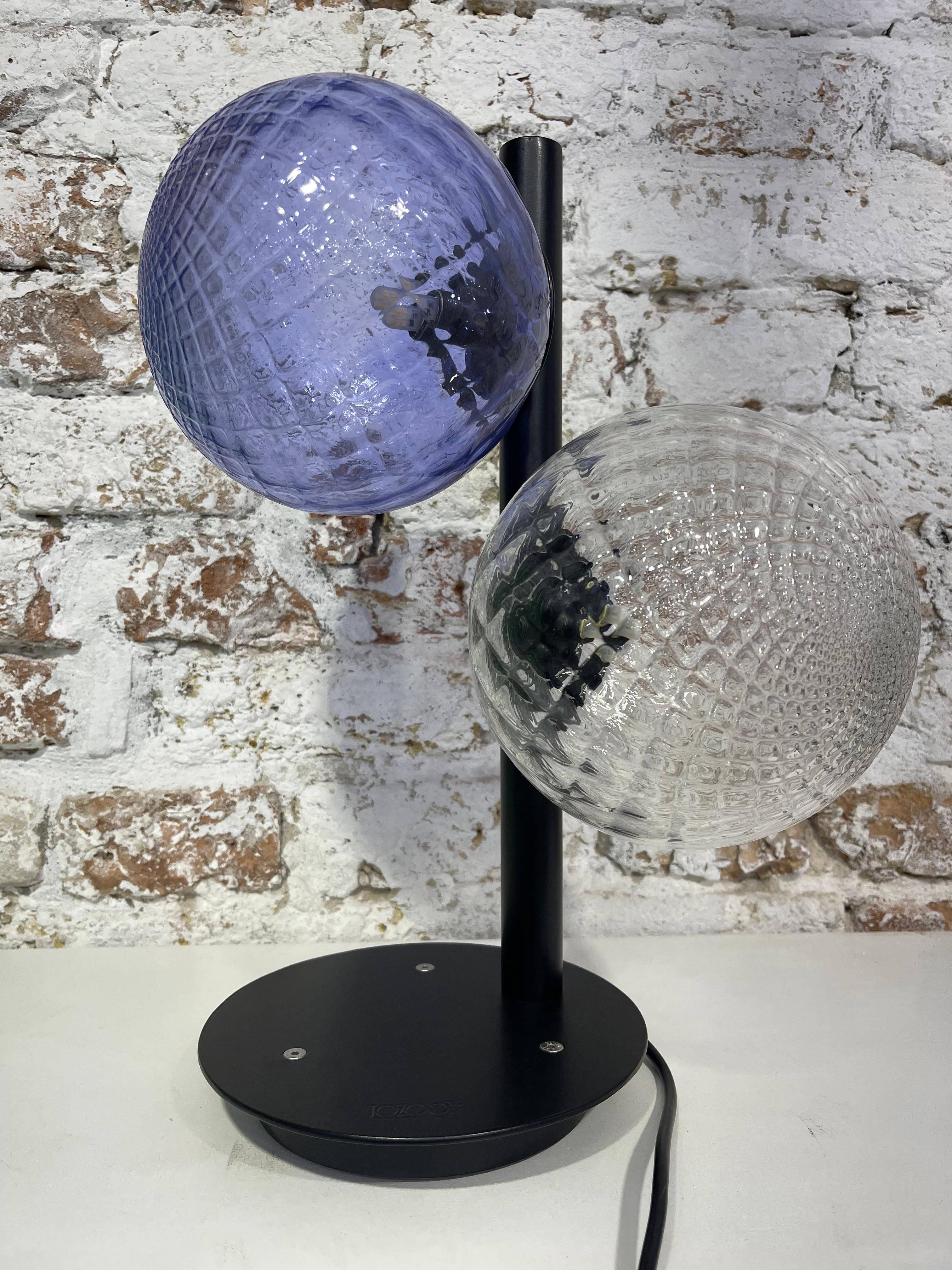 Contemporary, playful, and poetic are some of the adjectives that can be used to describe this table lamp, handmade in our family-owned furnace. Our lamps are composed of two handcrafted elements, a metal structure with an integrated dimming system