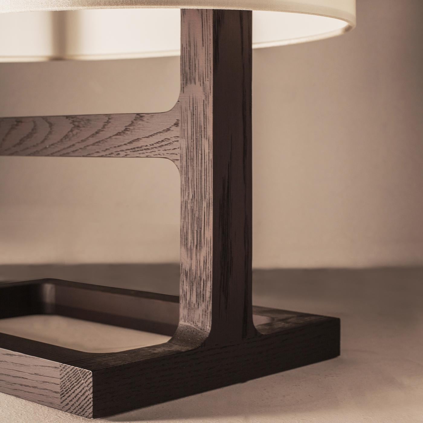 While the solid oak structure gives a solid, vintage look to the lamp, the textile diffuser gives it a touch of lightness. The result is an elegant table lamp, which belongs to the Tour collection. It is perfect to complete modern and classic