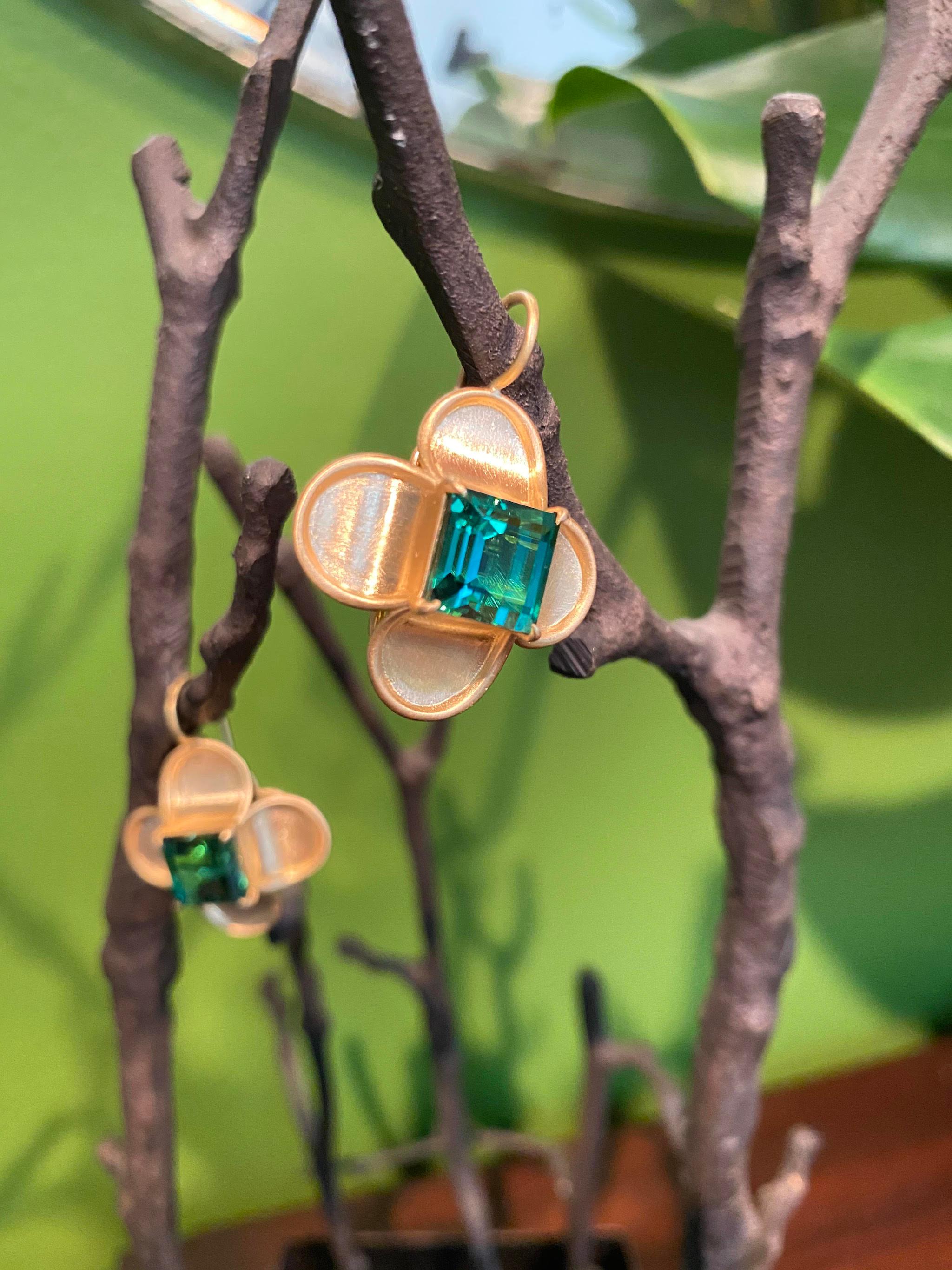 Each ear pendant set with a square rectangular gem quality bluish green tourmaline, within a stylized 'petal' setting typically seen during the Renaissance. The reverse of the ear pendants is decorated with a quatrefoil 'fleur de lys' pattern and