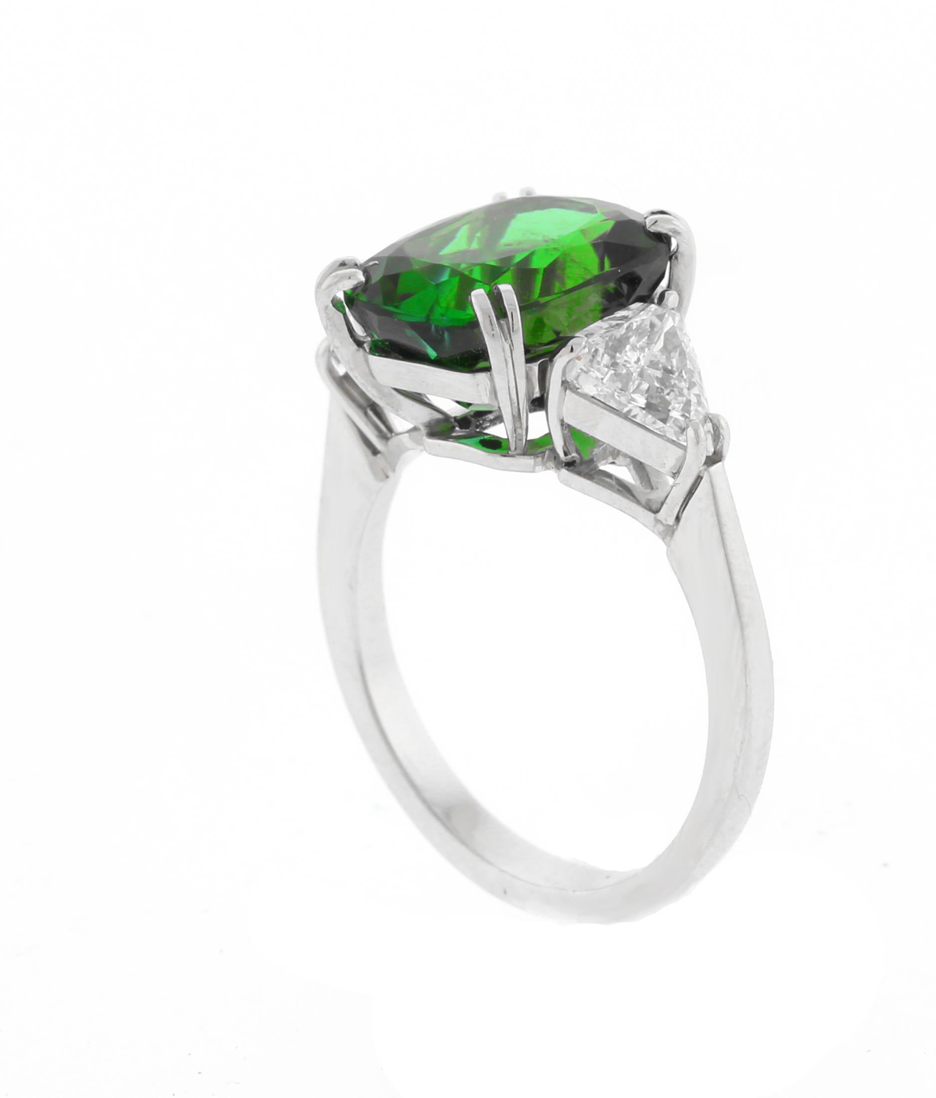 Réalisée par les maîtres joailliers de Pampillonia, cette exquise bague en platine faite à la main présente en son centre une étonnante tourmaline bleu-vert taillée en coussin, d'un poids de 4,81 carats. La pierre centrale est flanquée de deux